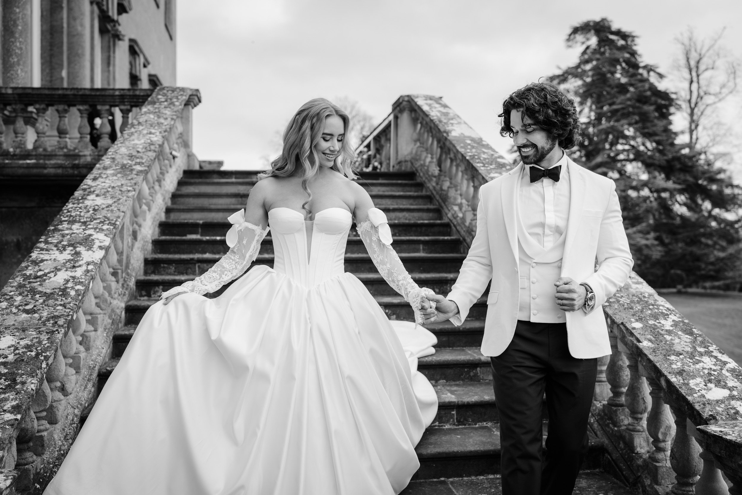 Bride and groom walking down the steps to the gardens  Kirtlington Park in Oxfordshire to greet there wedding guests