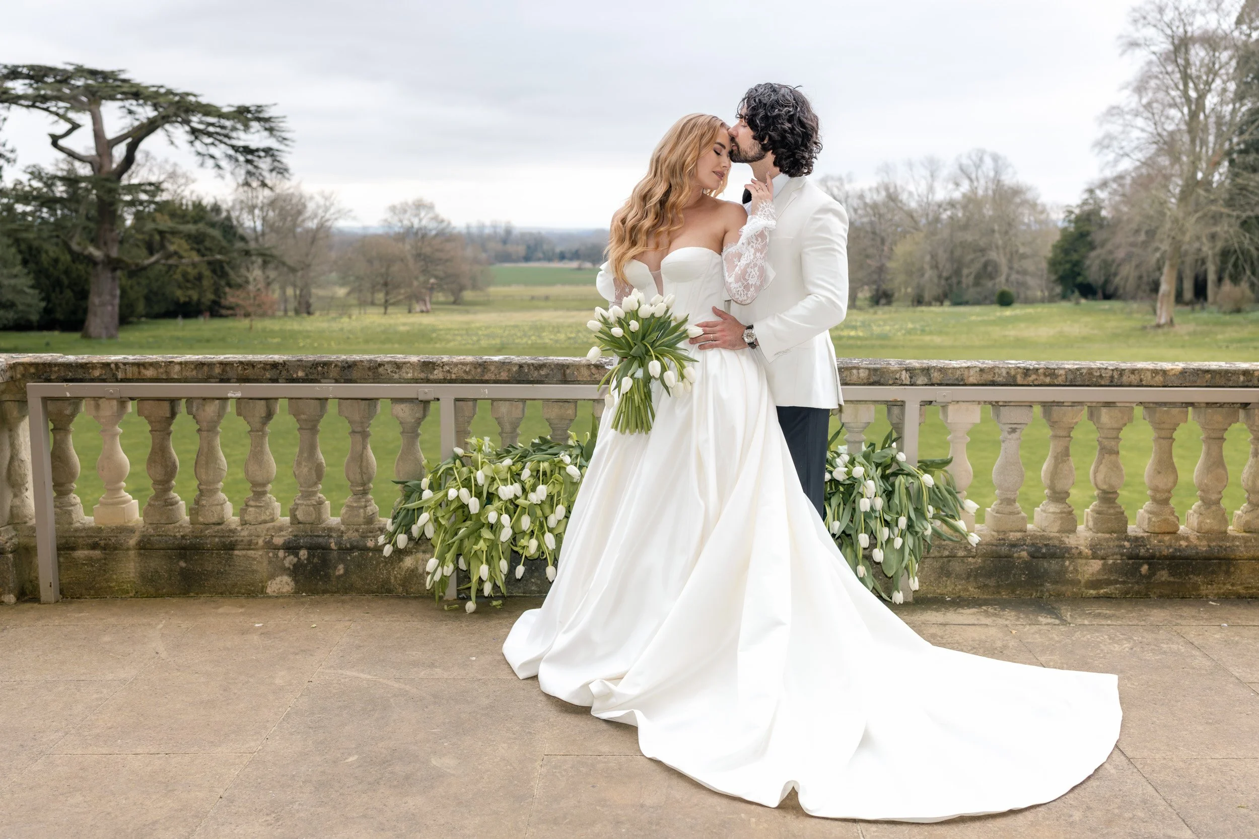 Bride and groom having an intimate moment on a floral balcony at Kirtlington Park in Oxfordshire