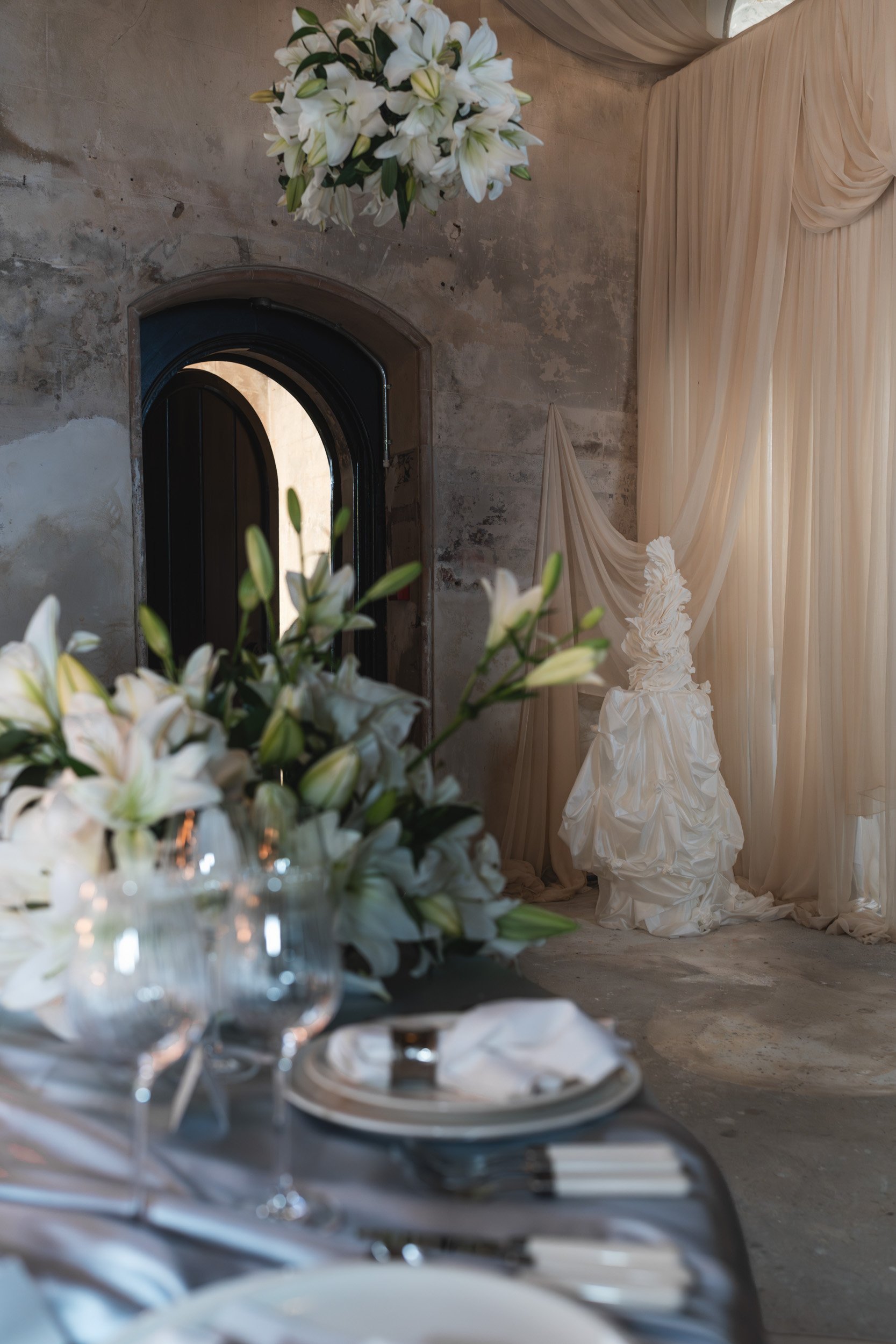 Wedding reception details candlelit reception room with draped fabric,  floral displays and the wedding cake  inside The Bell Tower at The Elvetham Hotel in Hampshire
