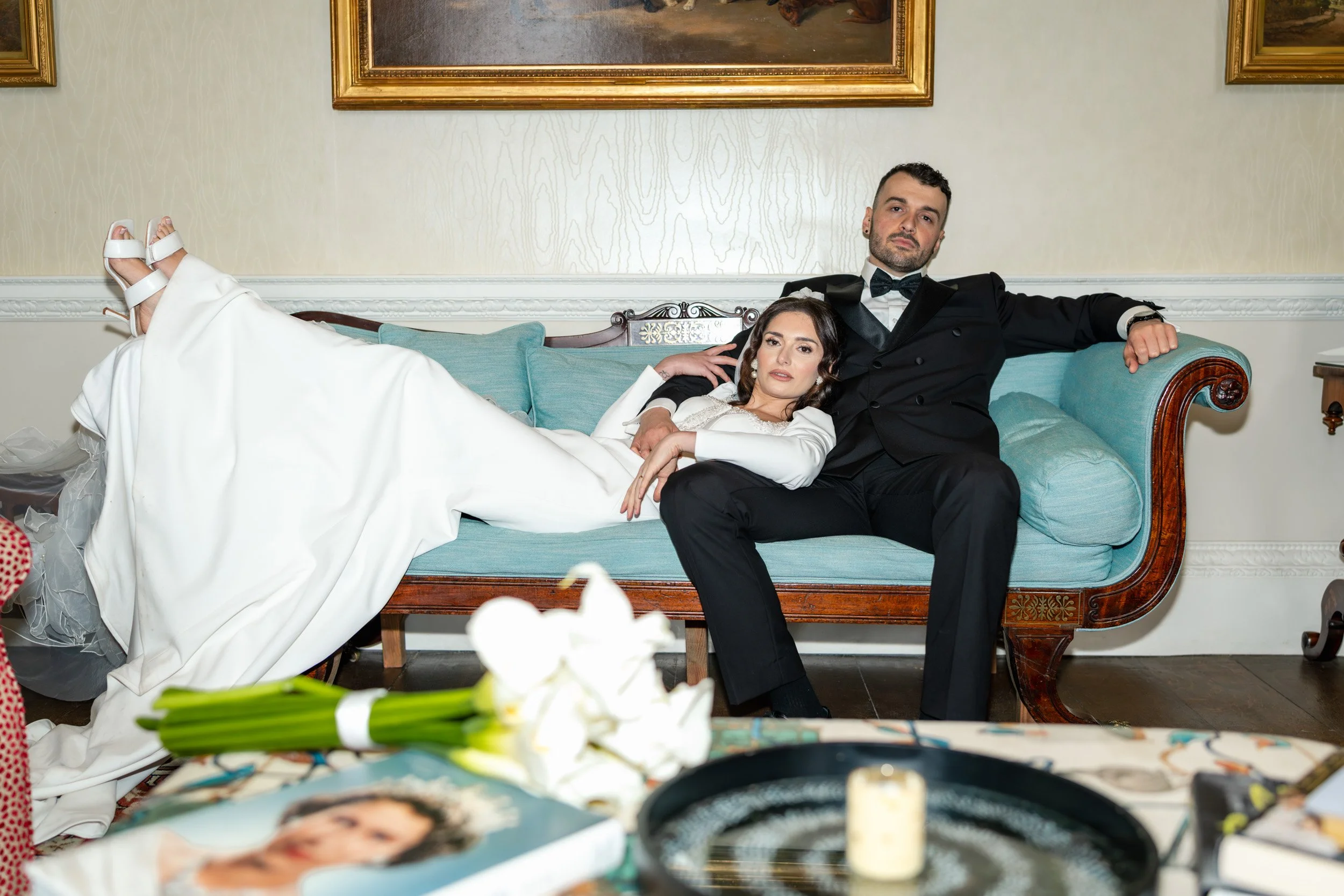 Bride and groom  lounging together on a sofa  at Kirtlington Park in Oxfordshire