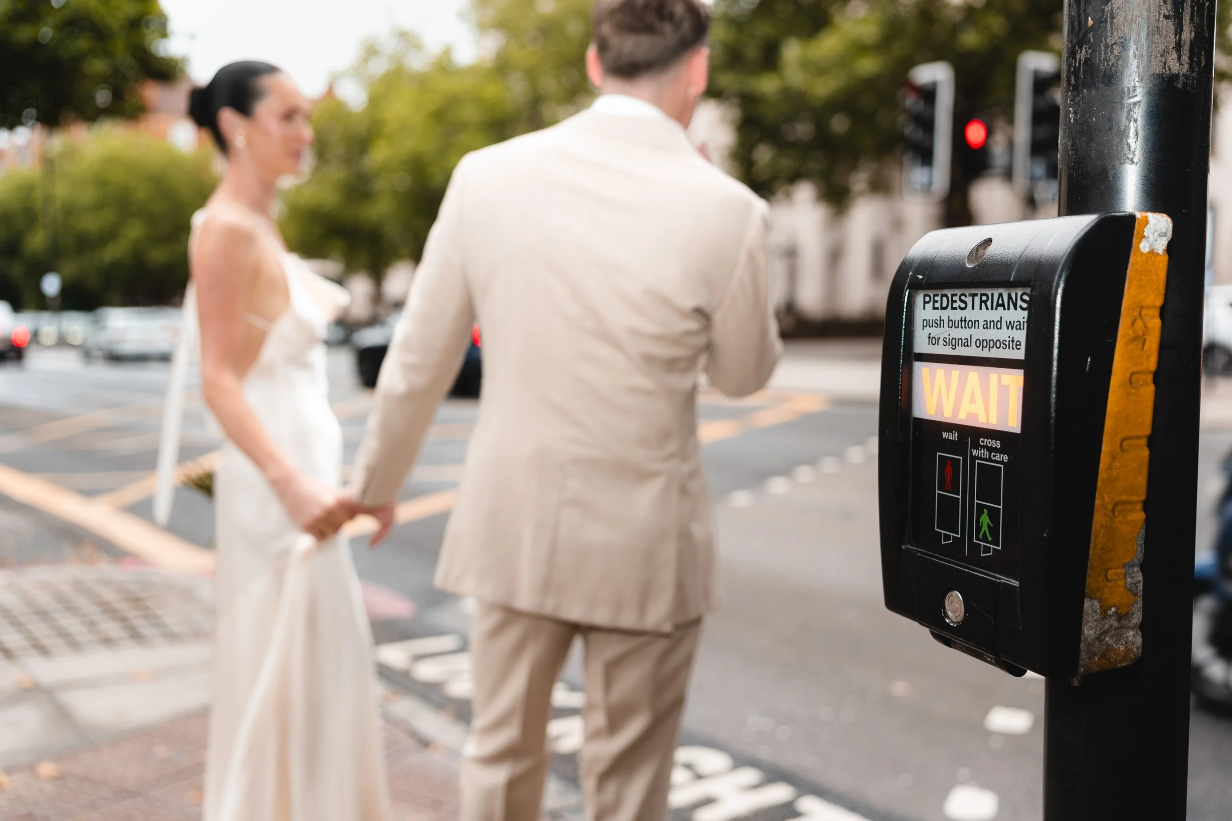 Close up of a ride and groom waiting at the pedestrian crossing on their way to Marylebone Town Hall Registry Office in London