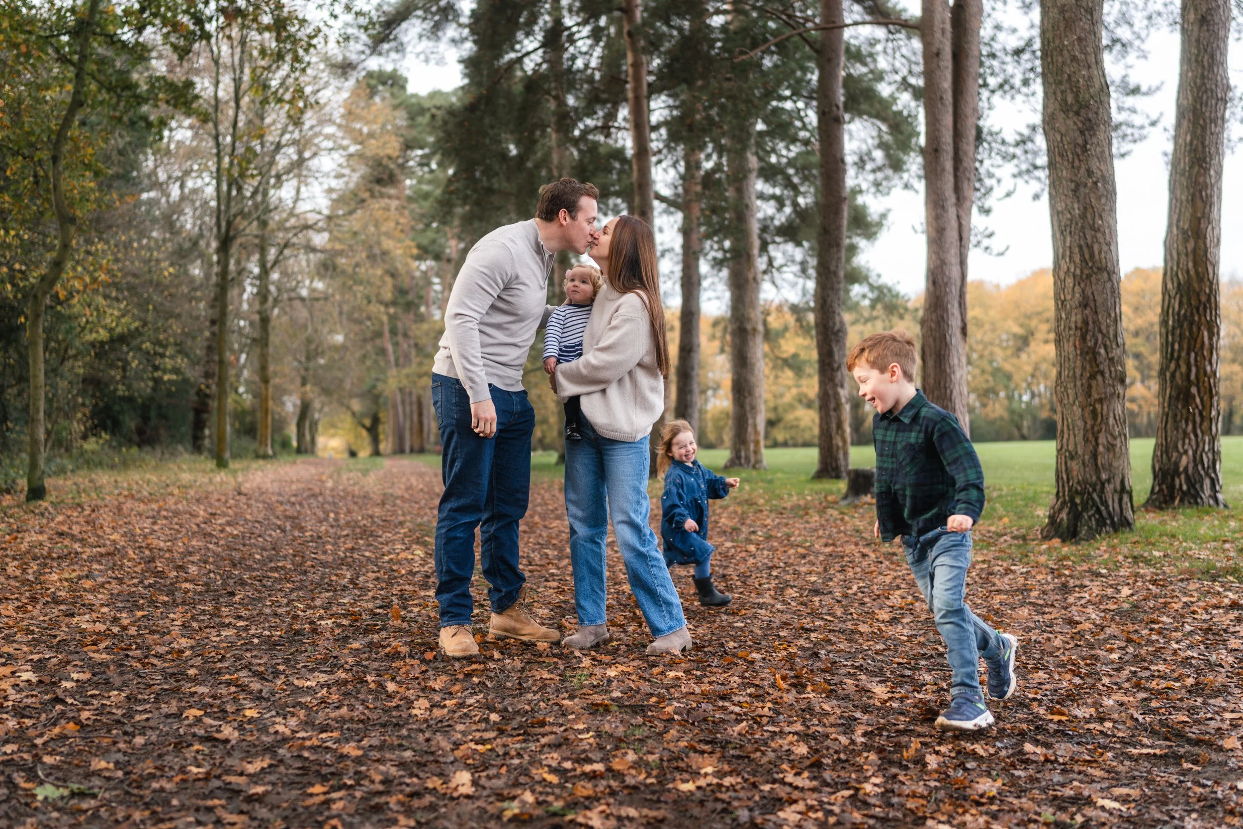 Family walking together through autumn leaves during a natural outdoor family photoshoot in Amersham, Buckinghamshire 