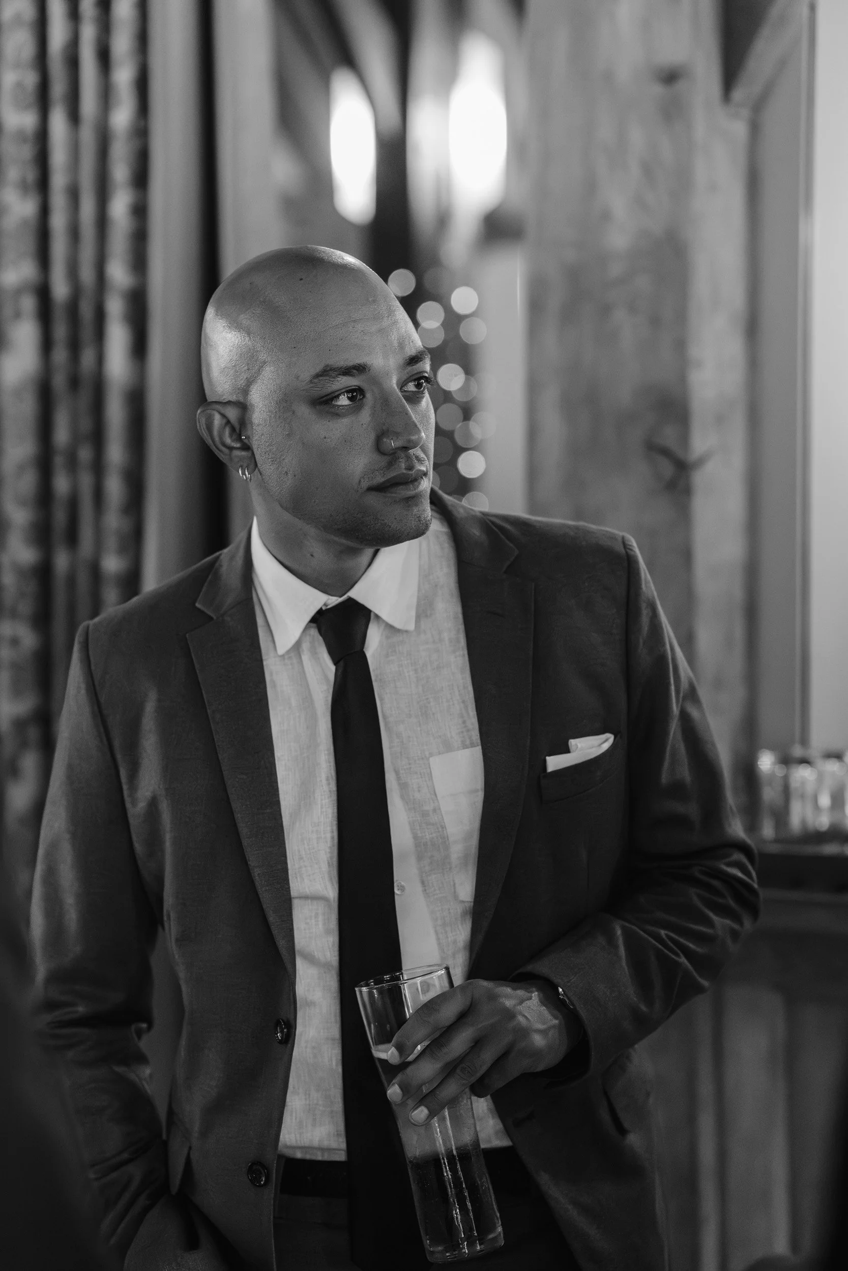 Best man holding a glass of champagne with his elbow on the bar during the wedding speeches at Rivervale Barn in Hampshire