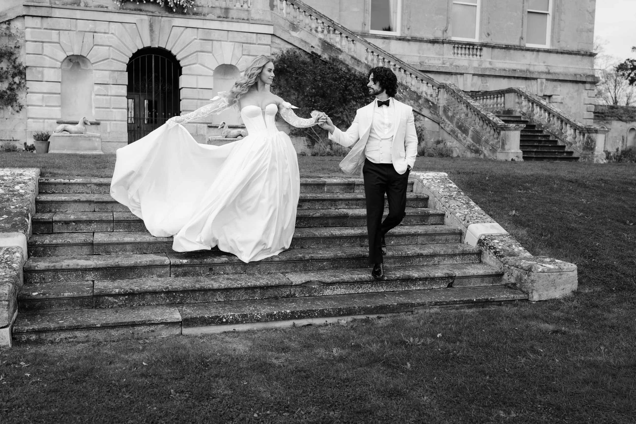 Bride and groom walking down the steps together outside Kirtlington Park in Oxfordshire