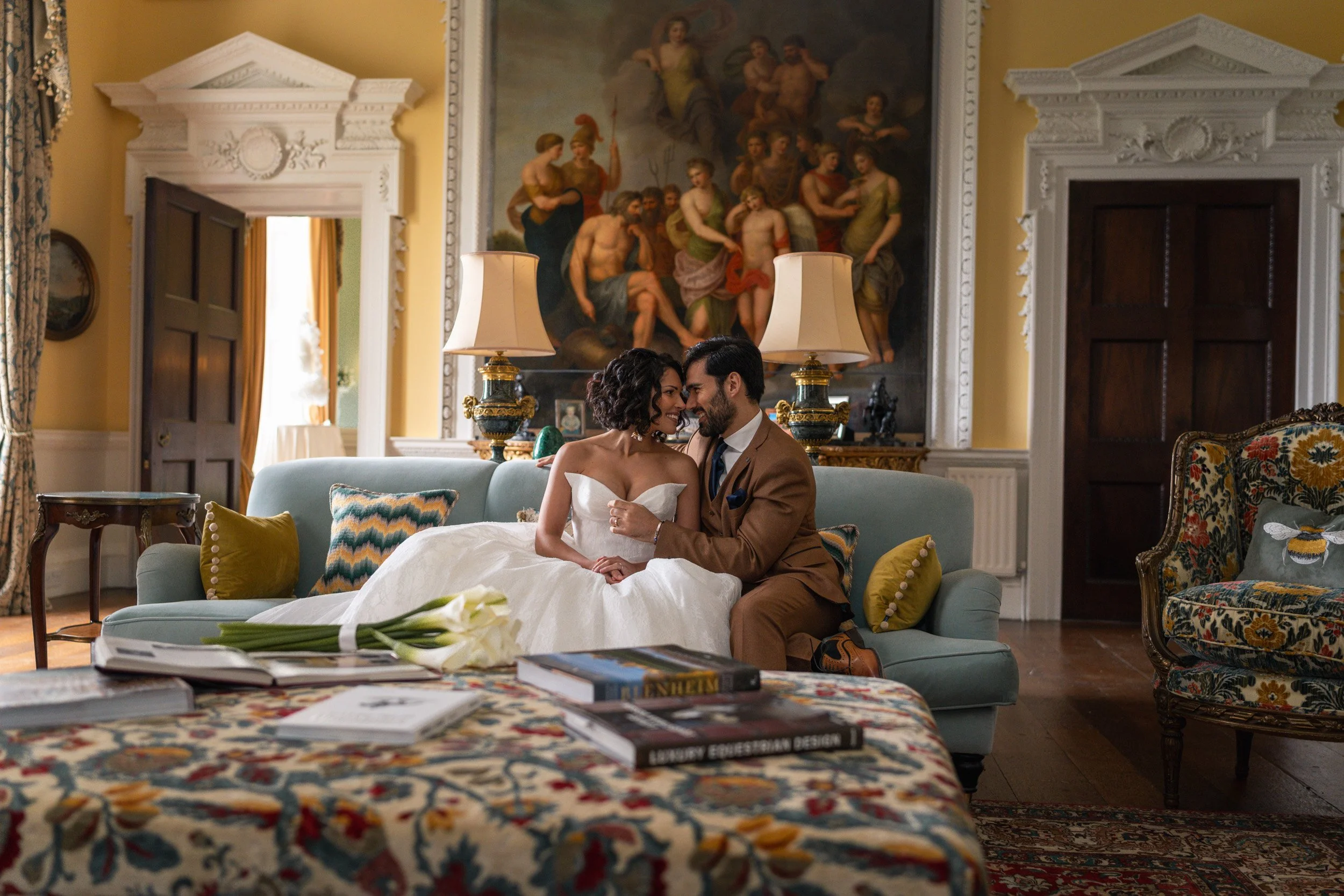 Bride and groom sharing an intimate moment together on a sofa in an elegant room at Kirtlington Park in Oxfordshire