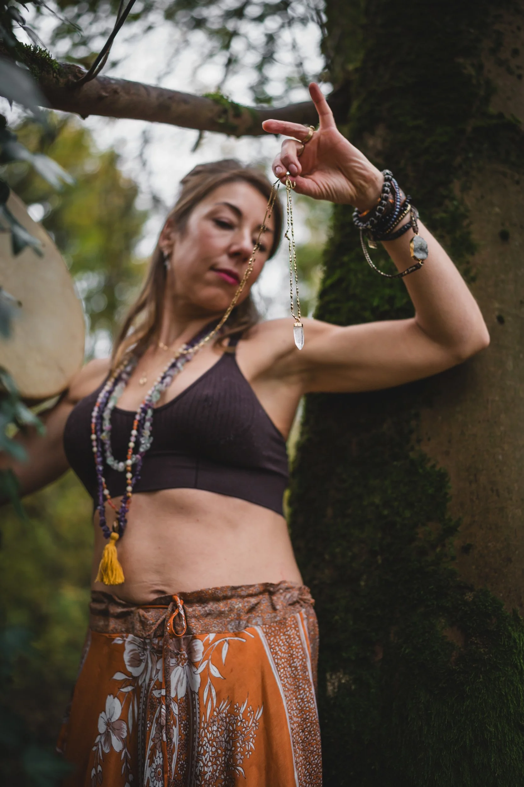 Sound healer using crystal dowsing pendulum during personal branding shoot in woodland near Amersham Buckinghamshire