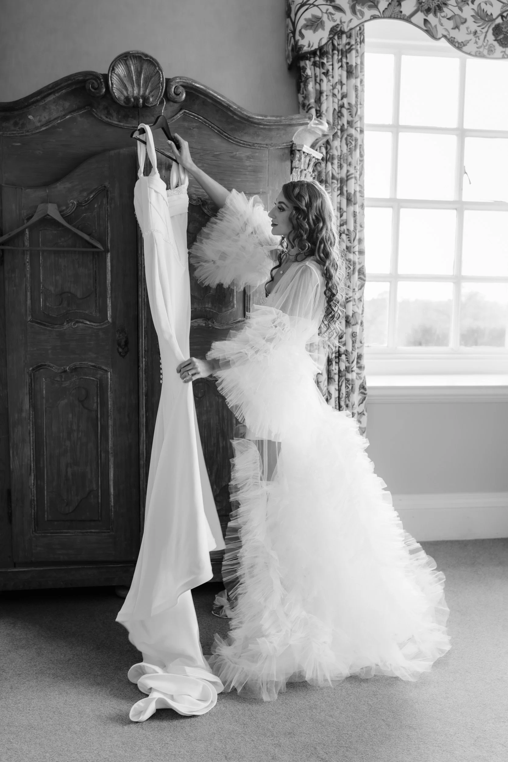 Bride in bridal lingerie and wedding gown looking at her wedding dress in the bridal suite at Kirtlington Park in Oxfordshire
