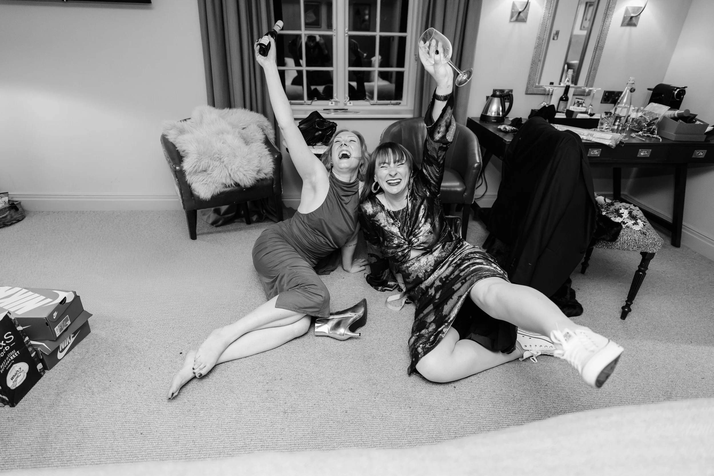 Bridesmaids laughing and cheering in the bride and grooms suit at a reception at The Bedford Arms in Chenies, Buckinghamshire