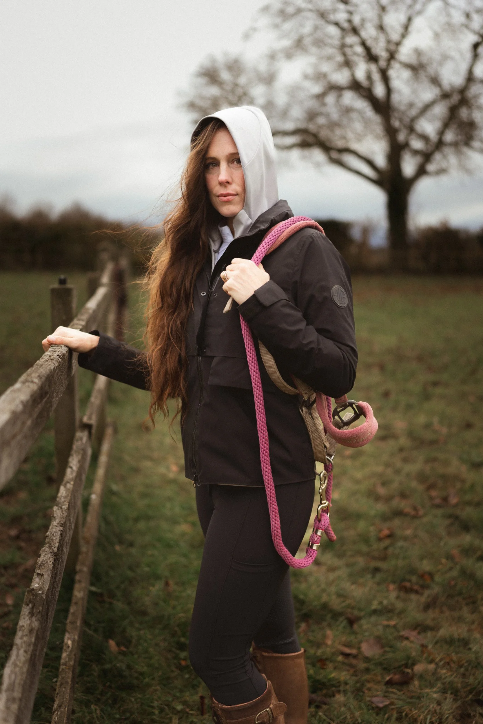 Equestrian fitness standing by paddock fence holding lead rope at Sean Hardy Horse Training in Great Missenden Buckinghamshire during a branding session