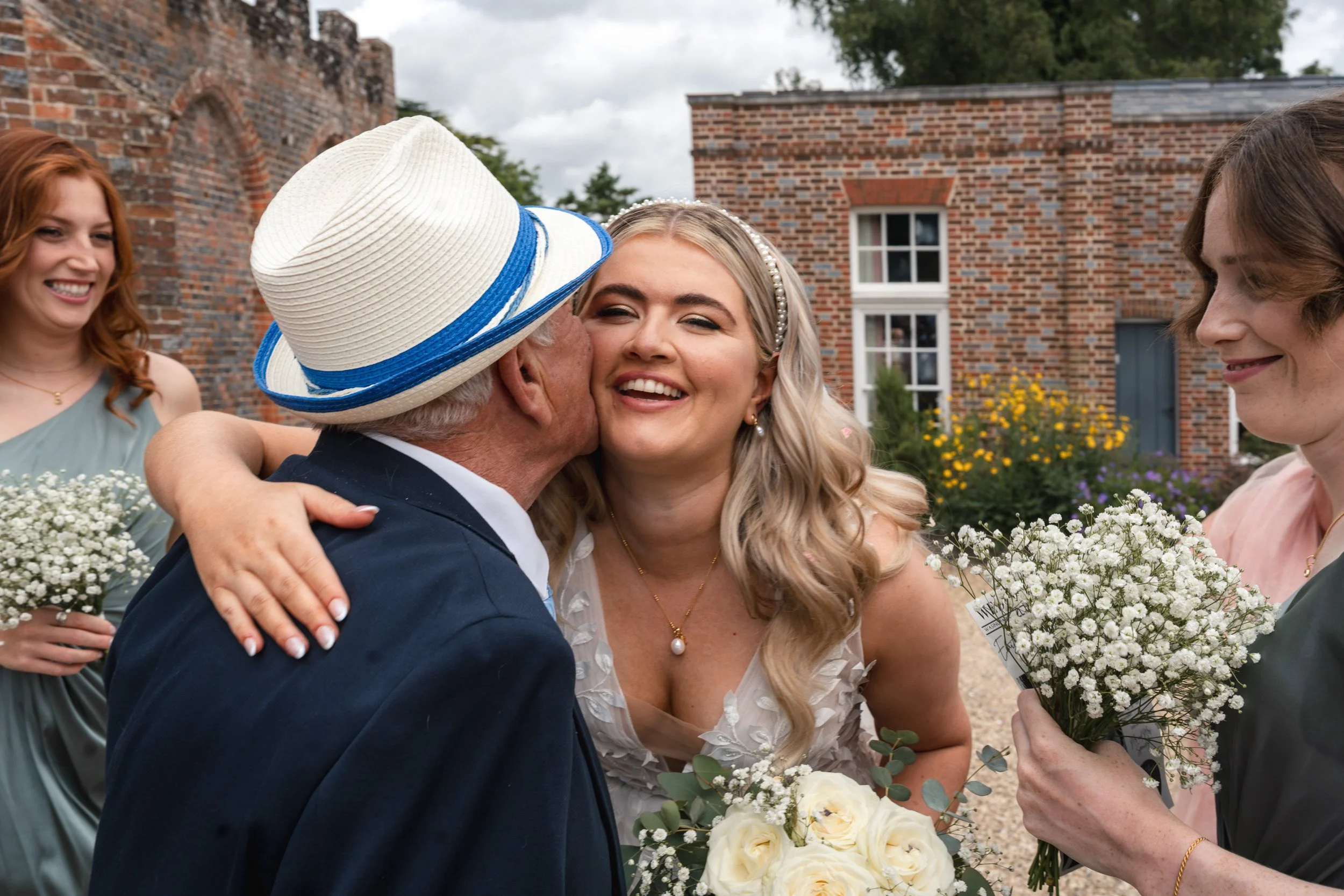 Happy bride hugs her grandfather amongst her bridesmaid flowers after an outdoor garden ceremony  Wasing Park in Berkshire
