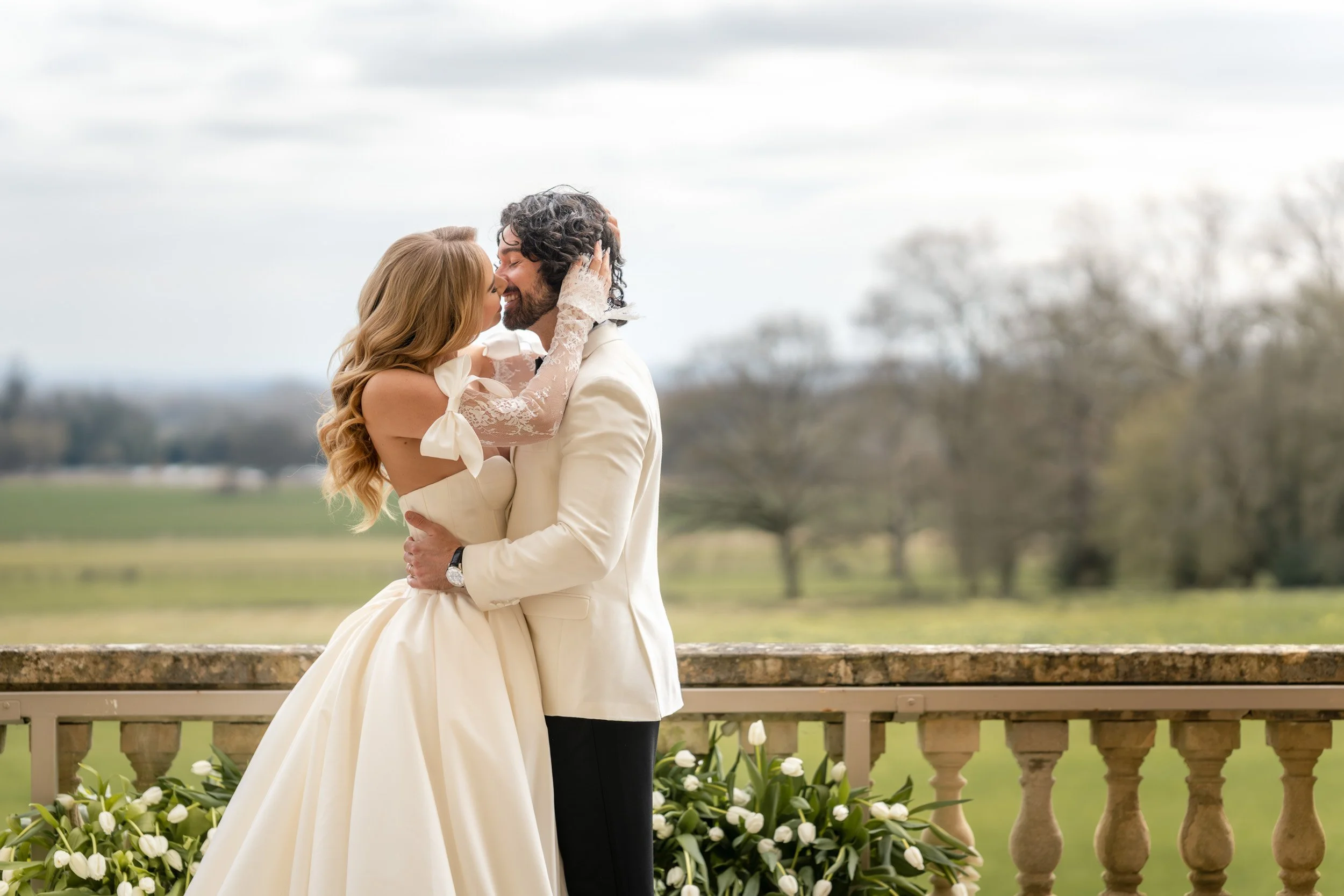 Bride and groom overlooking the gardens from a balcony at Kirtlington Park in Oxfordshire