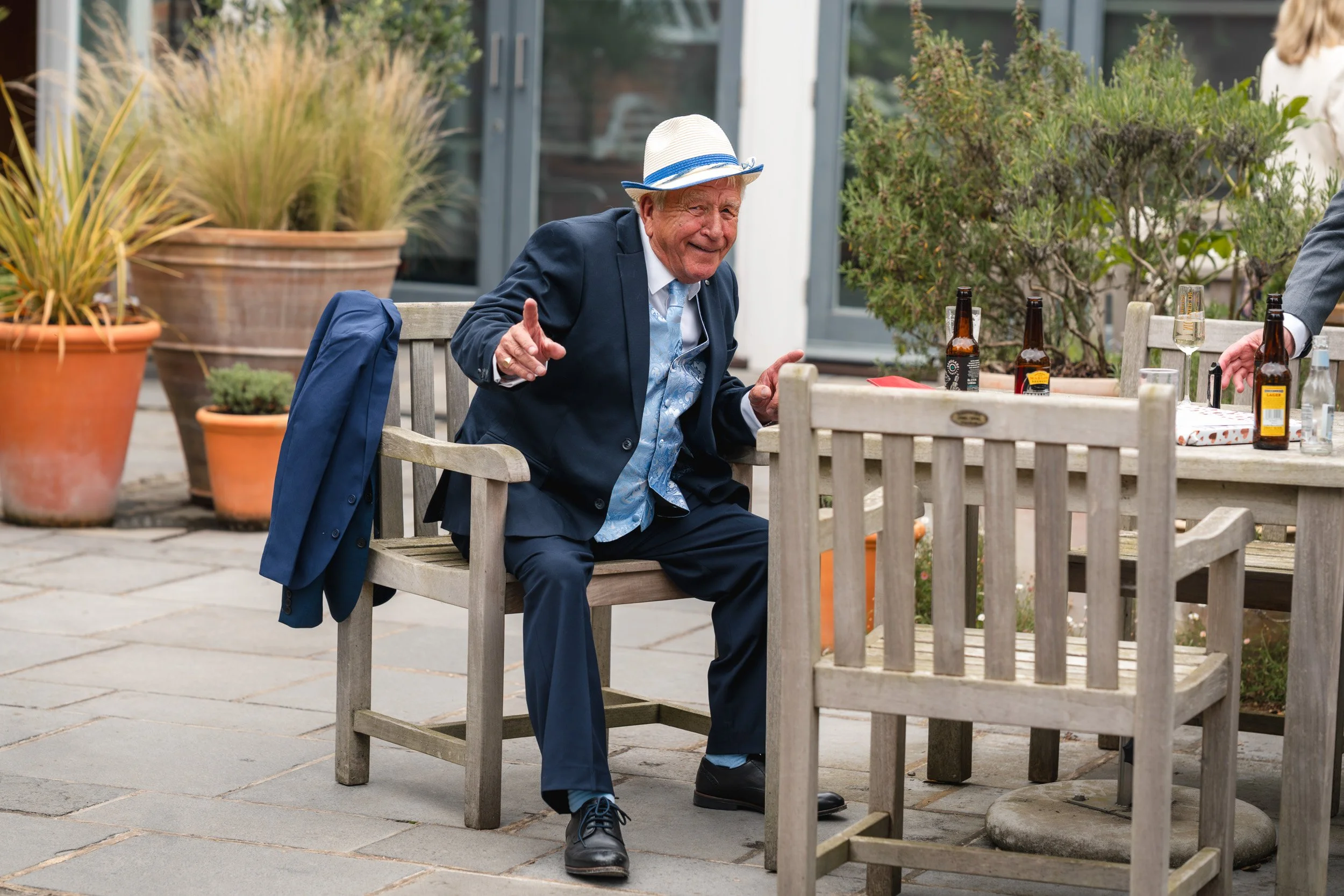 Guest giving a cheeky wave to the wedding photographer at a reception in.Wasing Park in Berkshire