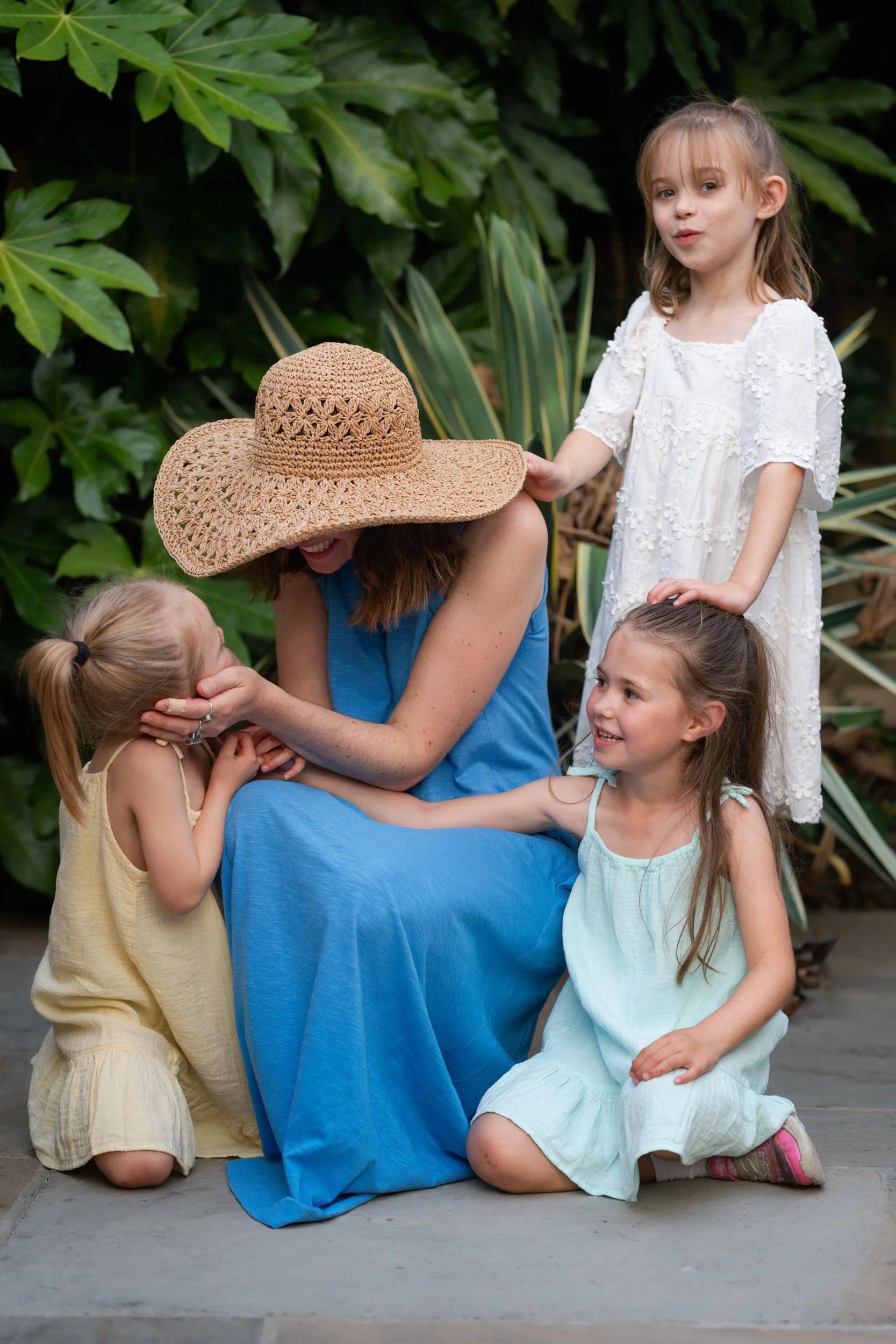 Mother surrounded by her young daughters during a natural motherhood photography session in Amersham, Buckinghamshire
