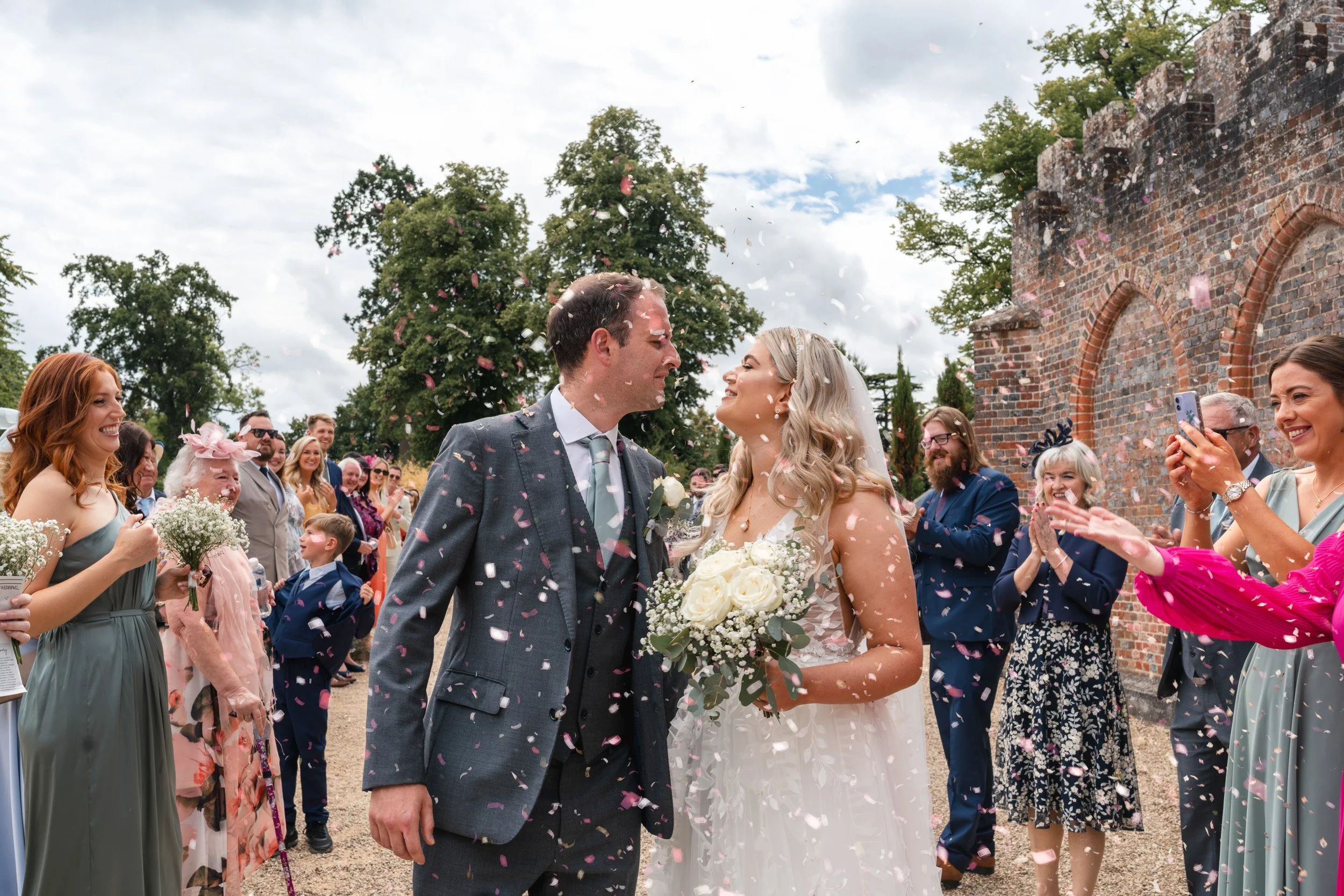 Bride and groom walking through confetti from their guests after the wedding ceremony at Wasing Park in Berkshire
