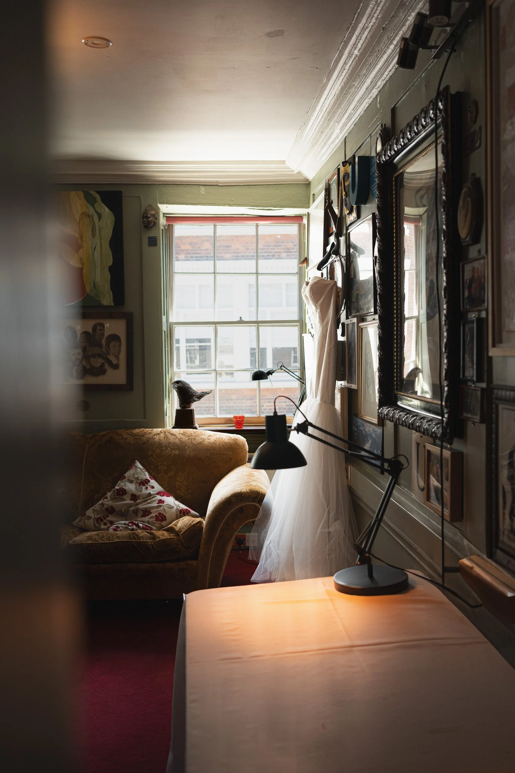 Side view of a wedding dress hanging on a gallery wall in a private room  at The Union Club in Soho, London