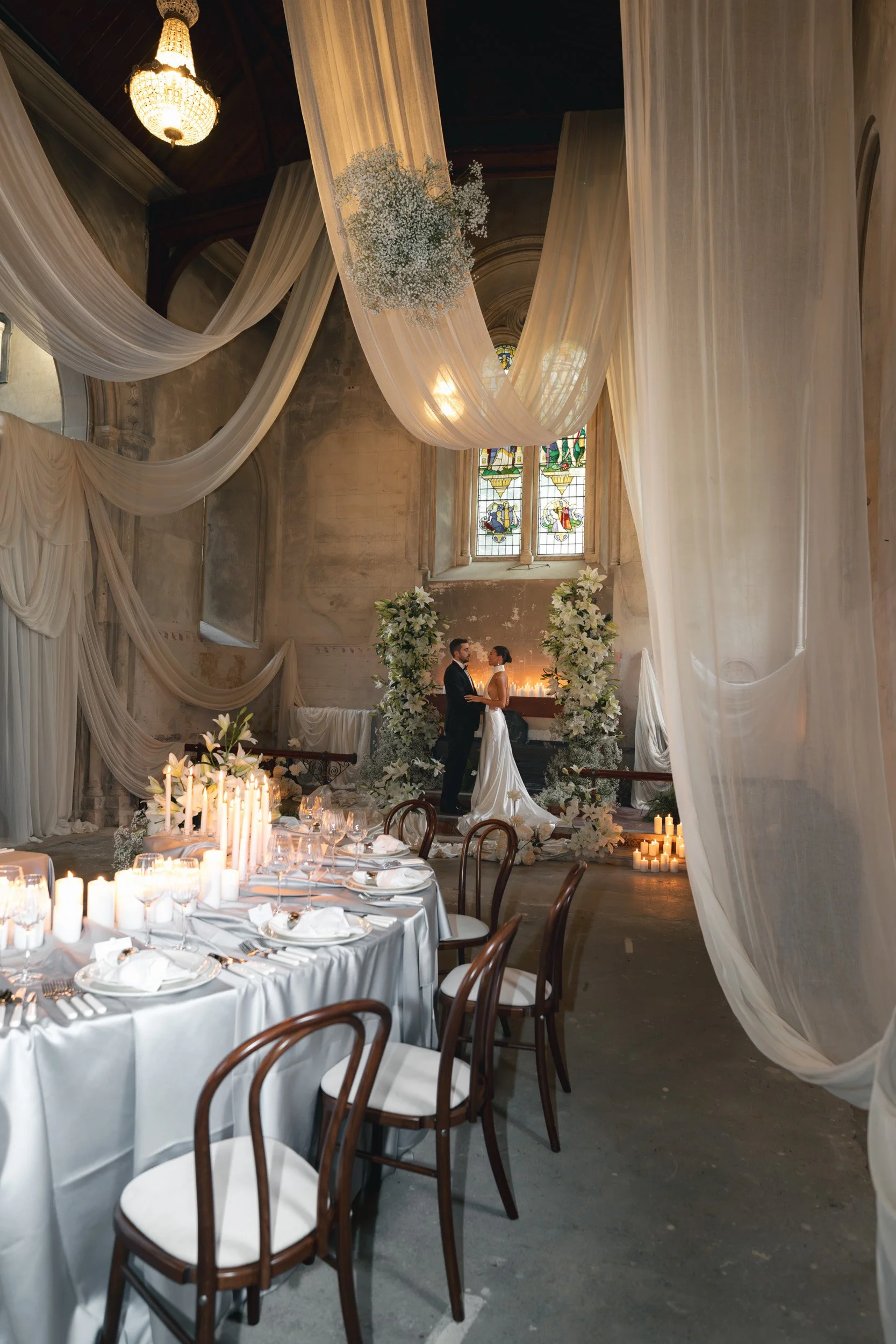 Bride and groom sharing an intimate moment in a  candlelit wedding reception with white florals and draperies inside  The Bell Tower at The Elvetham Hotel in Hampshire