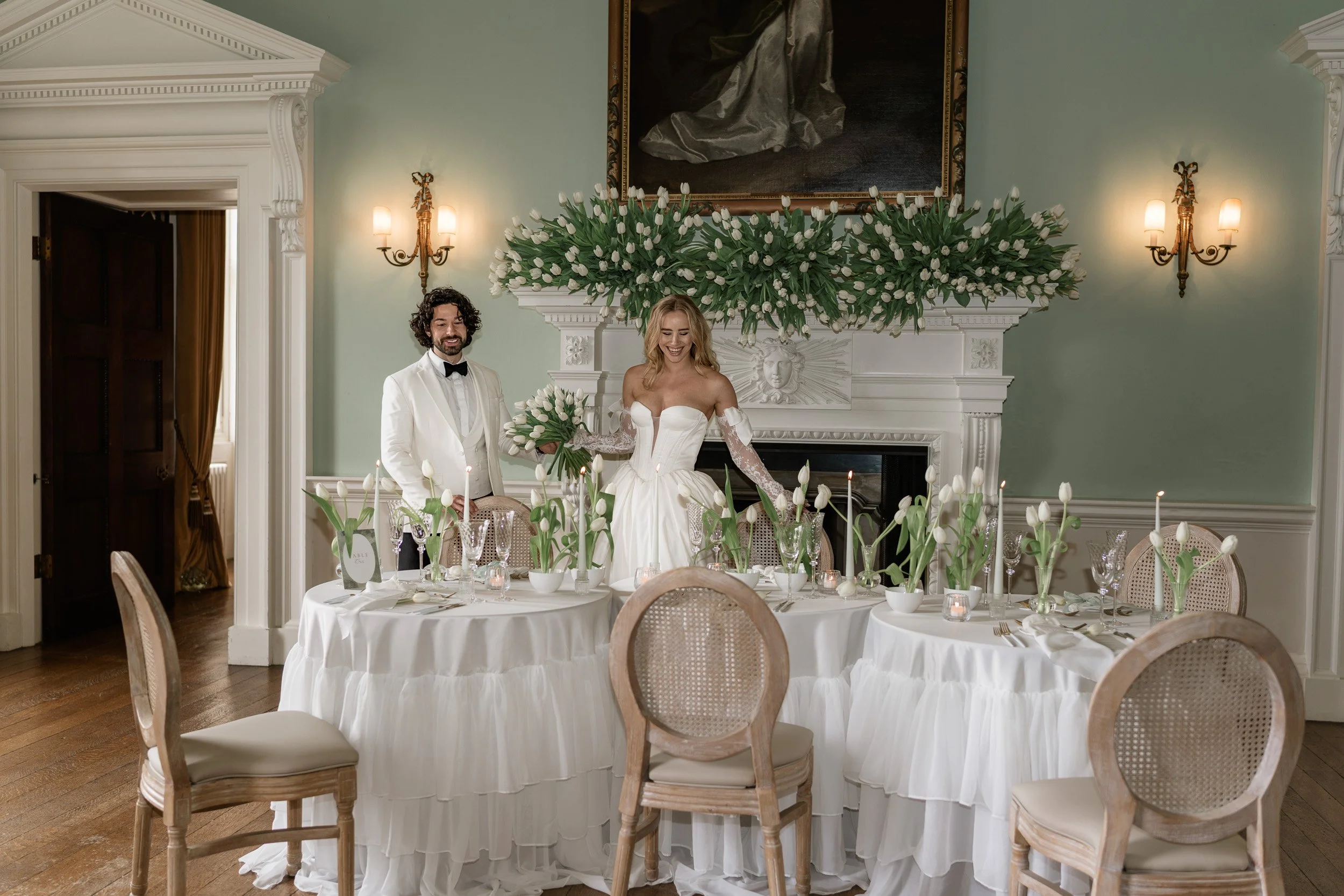 Bride and groom  admiring their candle and flower-lined head table at Kirtlington Park in Oxfordshire