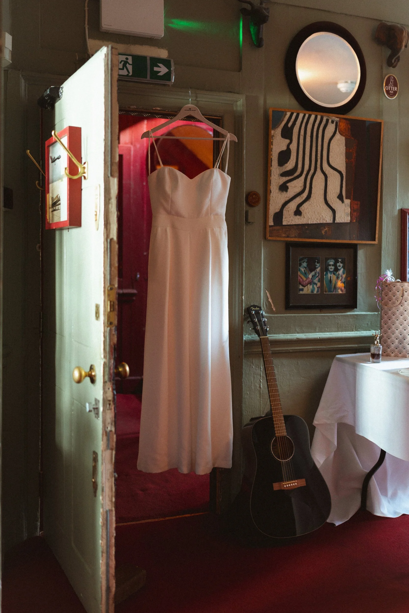 Wedding dress hanging in a doorway beside a guitar at The Union Club in Soho, London