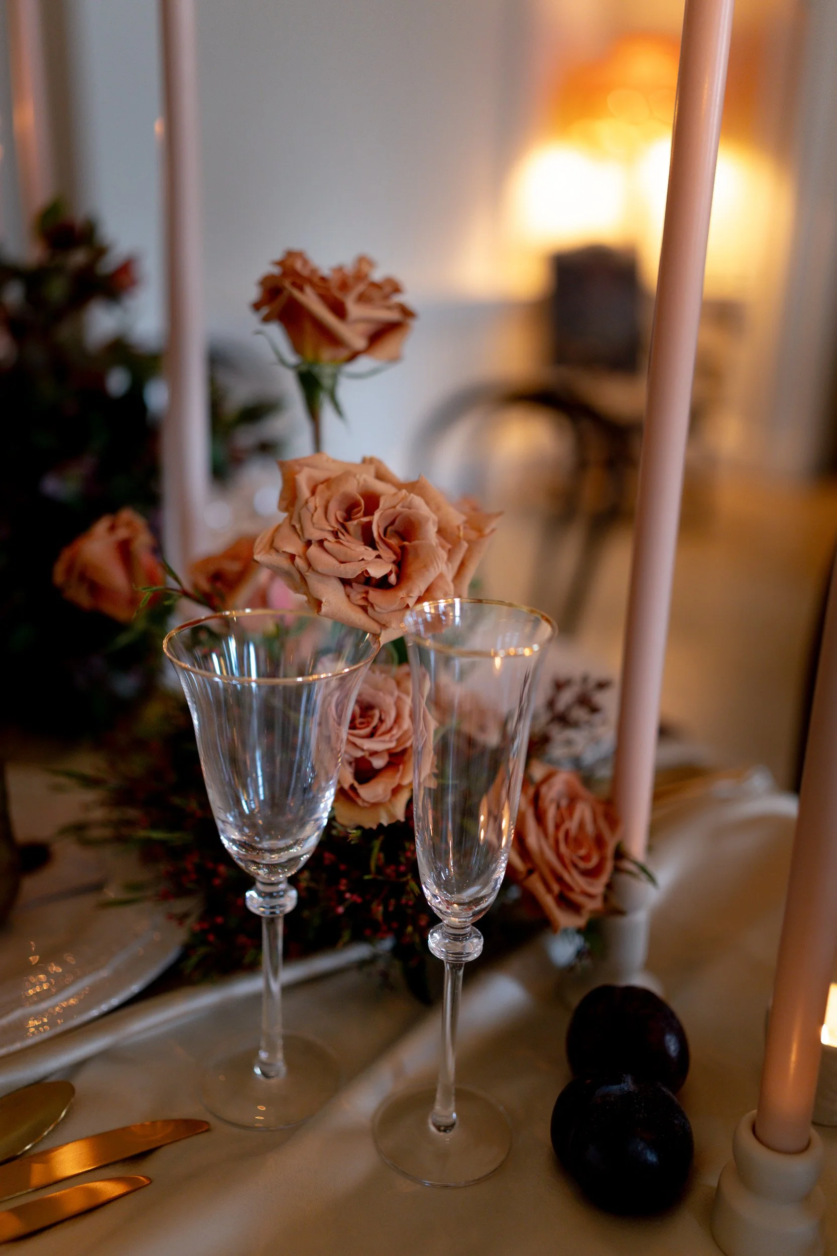 Floral and candle lit table setting at a wedding reception at Kirtlington Park in Oxfordshire featuring soft pink florals and candles
