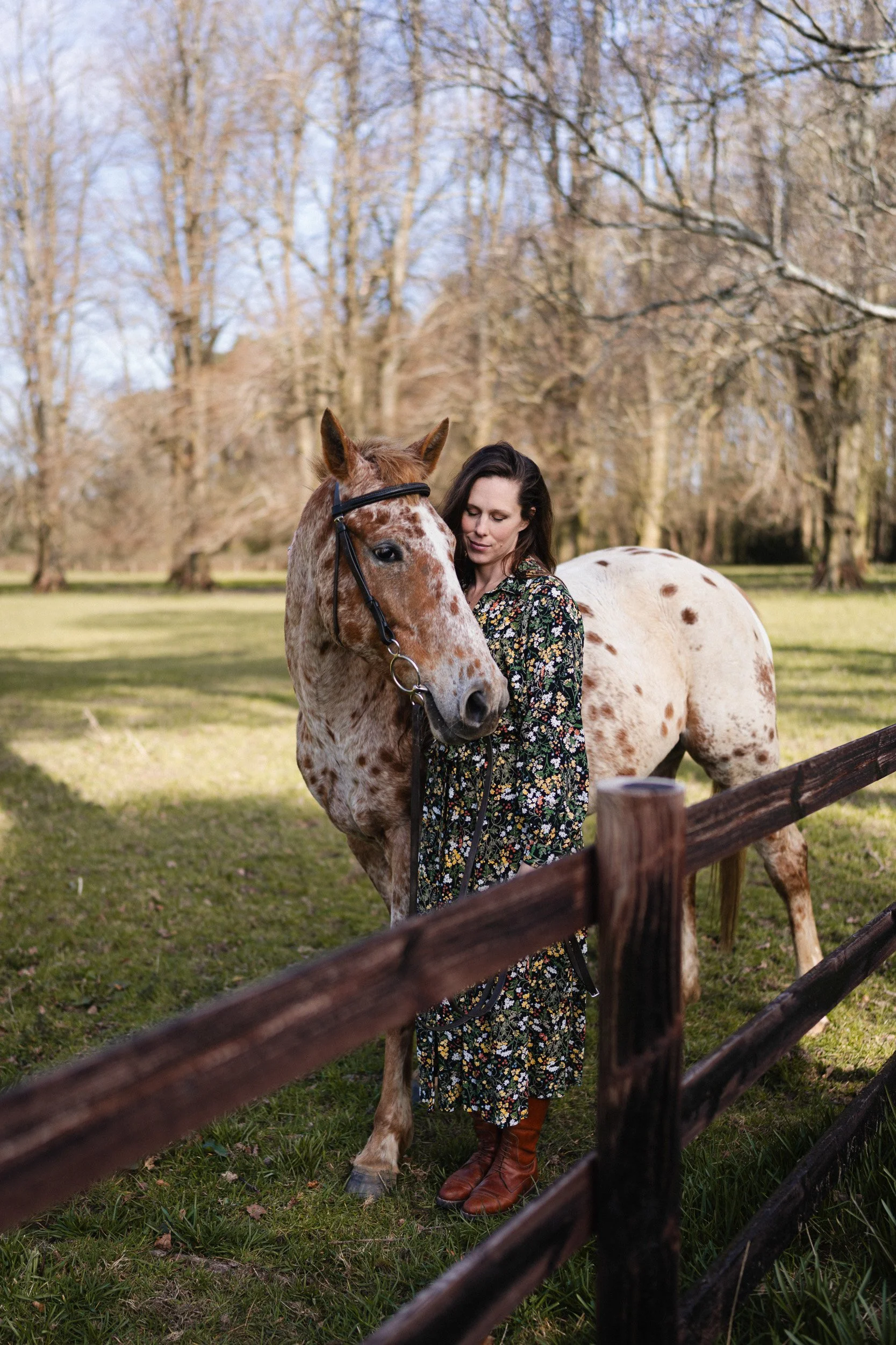 Equestrian fitness coach standing with Appaloosa polo pony in a paddock during a branding photoshoot at a polo club in Penn Buckinghamshire