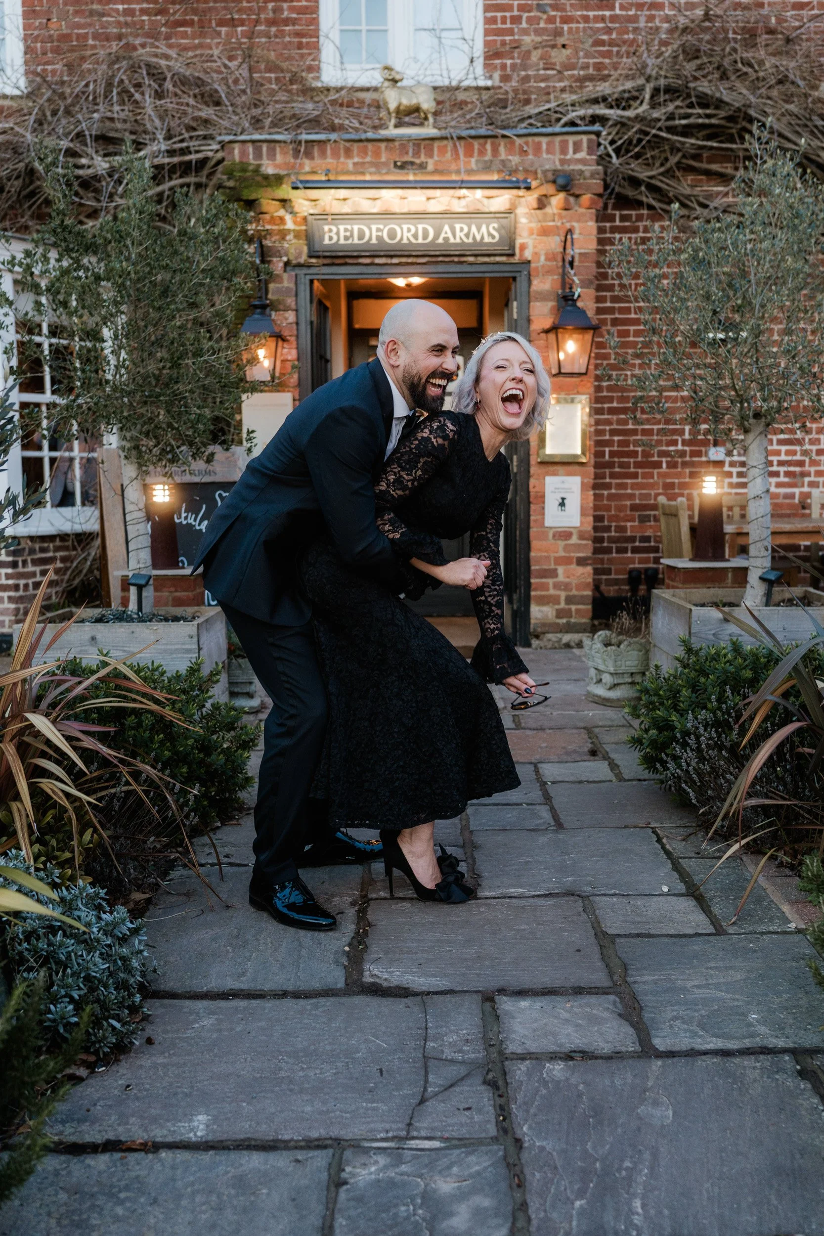 Bride and groom laughing together outside  The Bedford Arms in Chenies, Buckinghamshire during their wedding reception