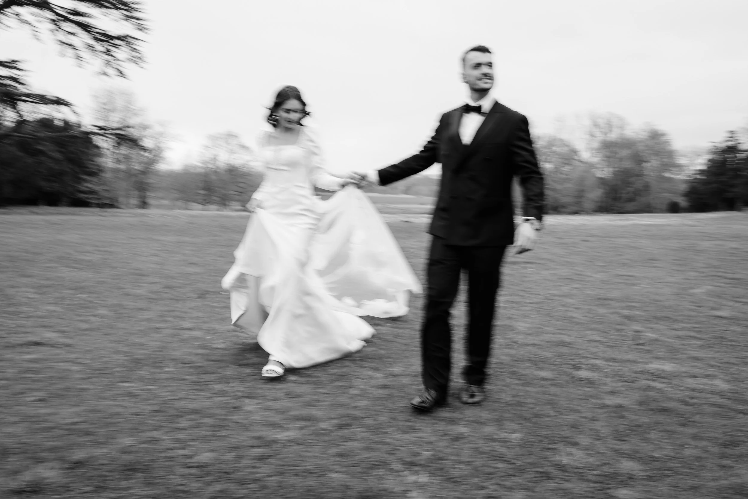 Bride and groom walking hand in hand with soft motion blur in the gardens of Kirtlington Park in Oxfordshire