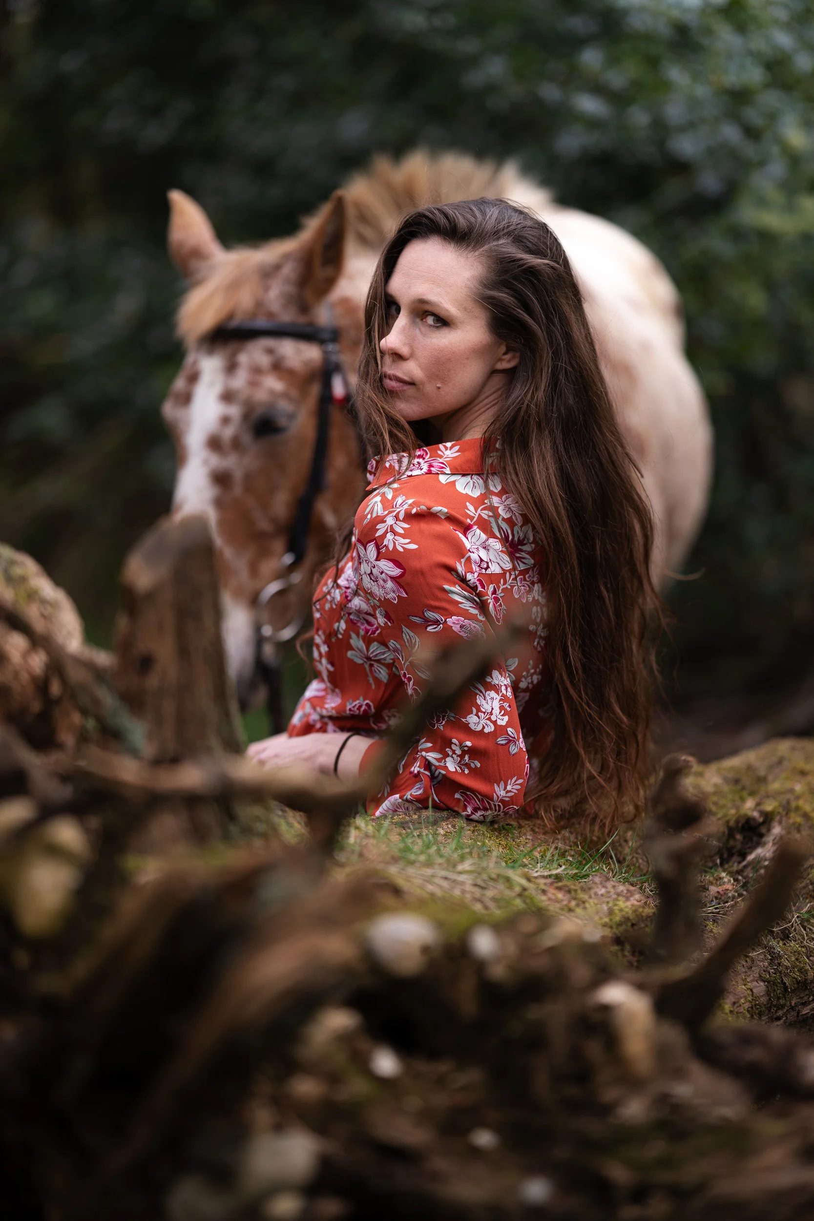 Close up of an equestrian fitness coach sitting on a log in the woodland with an Appaloosa polo pony  brand photoshoot in Penn Buckinghamshire