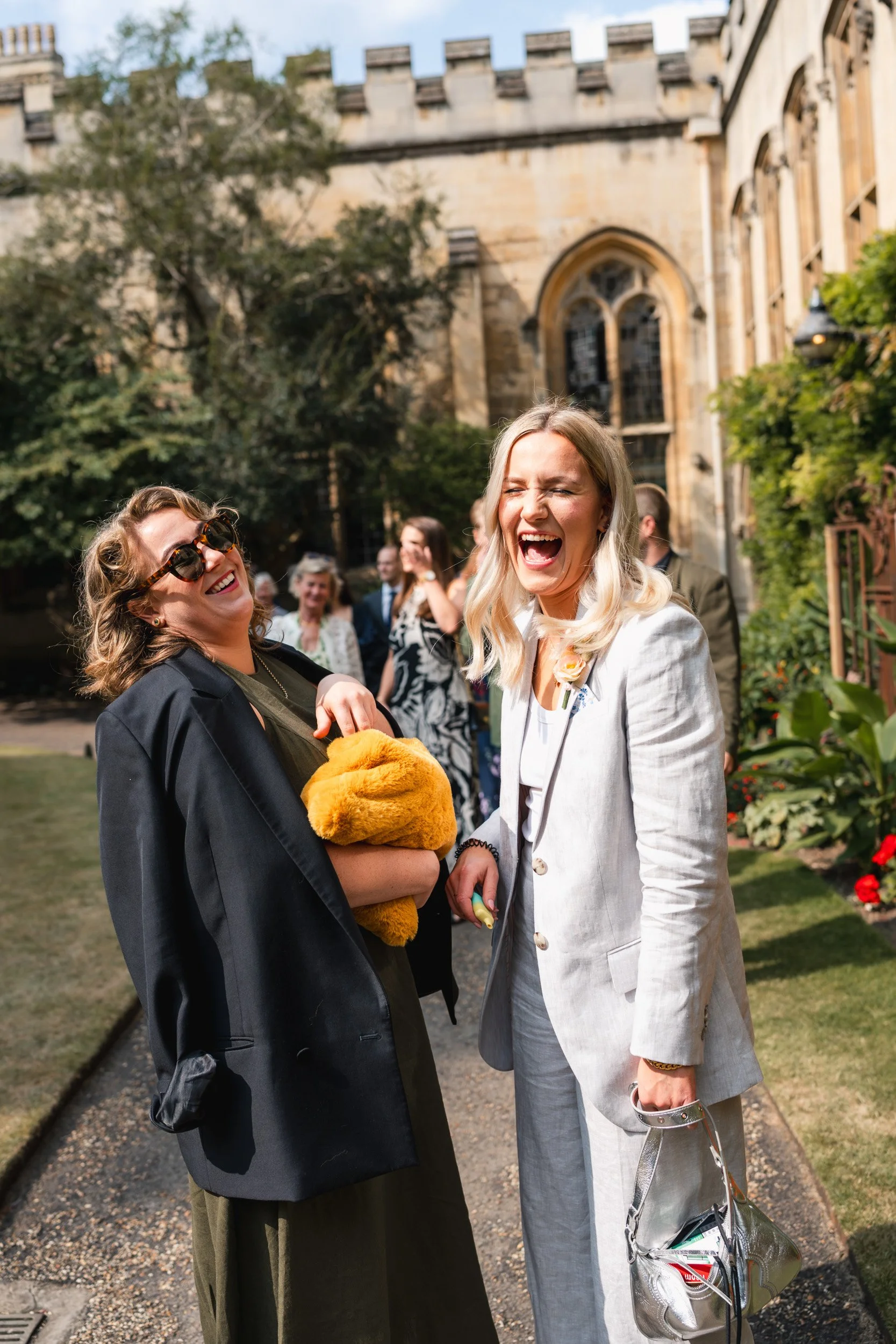 Wedding guests laughing in the courtyard  of an Oxford University college before the wedding ceremony in Oxford, England