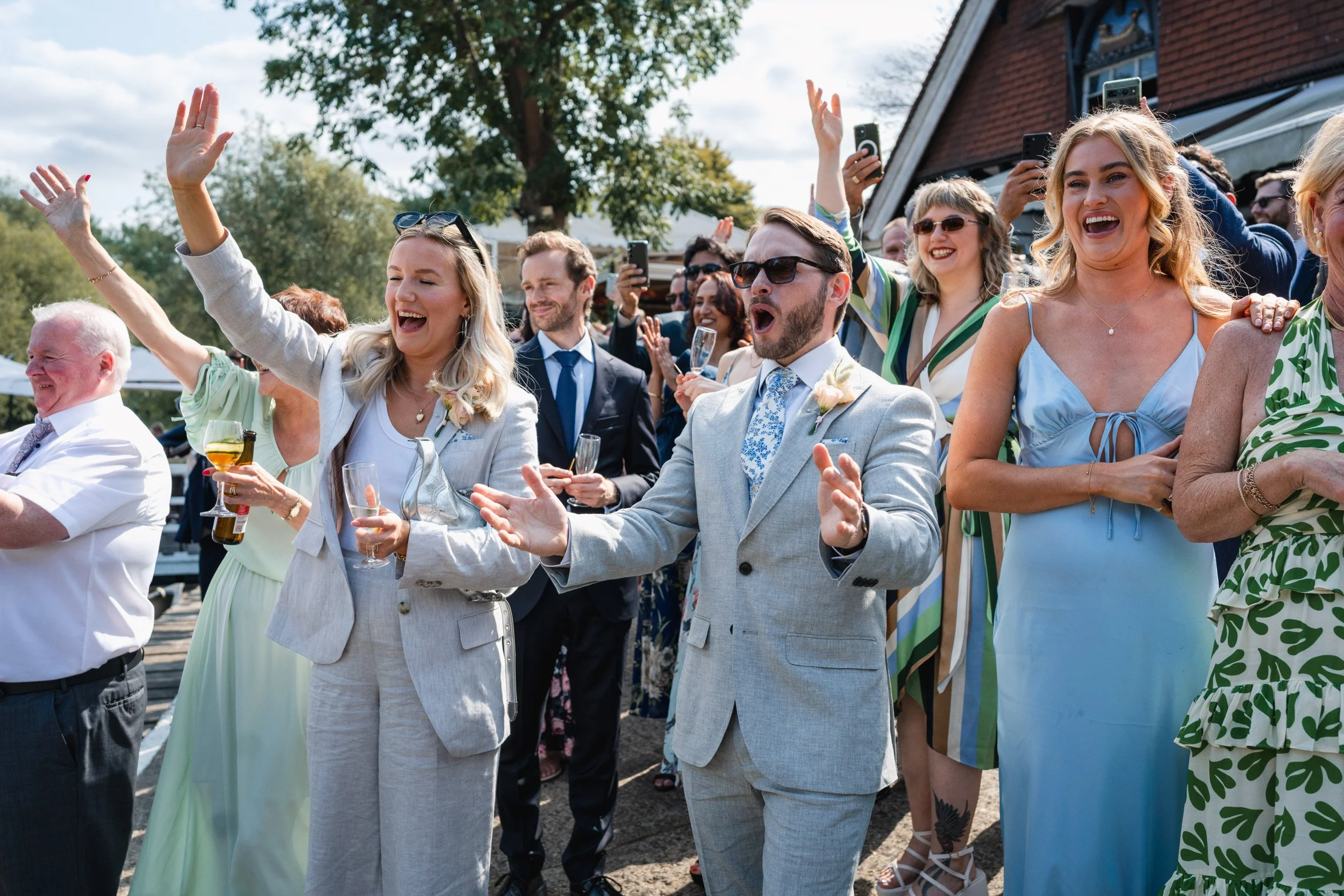 Wedding guests cheering and celebrating as the  bride and groom arrive by punt boat at Cherwell Boathouse in Oxford 
