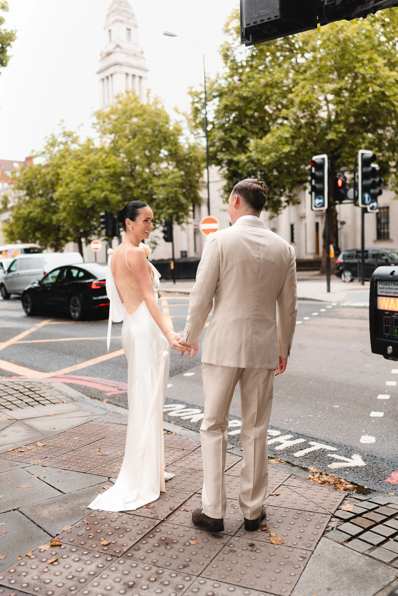 Bride and groom waiting at the pedestrian crossing on their way to Marylebone Town Hall Registry Office in London