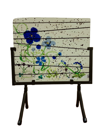 A decorative blue flowers and green vines  piece featuring black horizontal lines and speckled black dots on a metal stand.