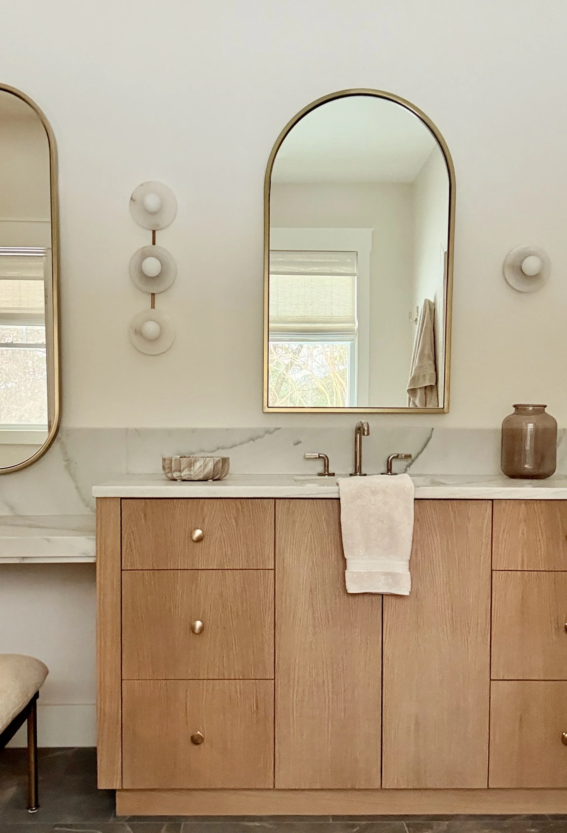 Bathroom cabinet in white oak with quartzite countertops, arched brass mirror, and vanity sconces with natural stone.