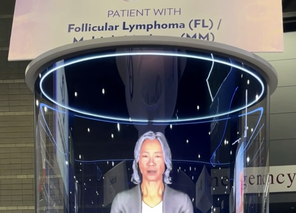 Virtual assistant's image of an elderly woman with gray hair, displayed on a digital screen inside a curved glass enclosure with glowing blue rings and starry background, related to follicular lymphoma.