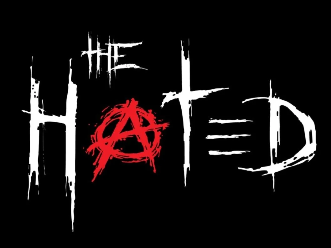 Stylized black background with the phrase 'The Hitched' written in white and red, with the letter 'A' in the middle depicted as an anarchy symbol.