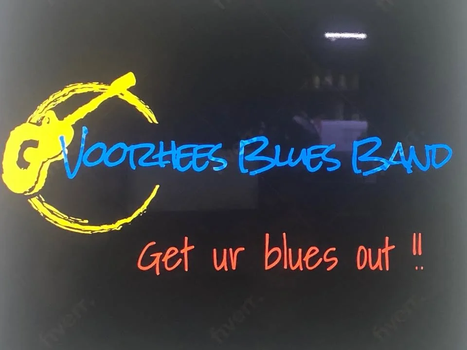 Logo for Voorthees Blues Band featuring a yellow guitarist icon, band name in blue, and tagline 'Get ur blues out!!' in red.