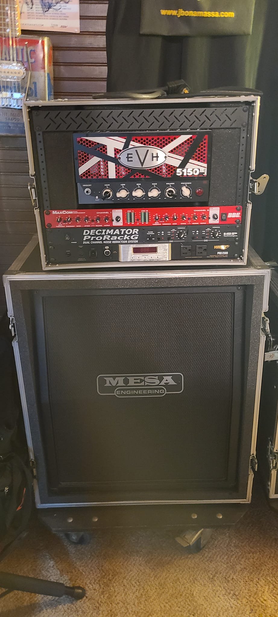 A PA speaker cabinet, with audio equipment stacked on top, including a guitar amplifier head, a multi-channel effects processor, and a speaker cabinet.