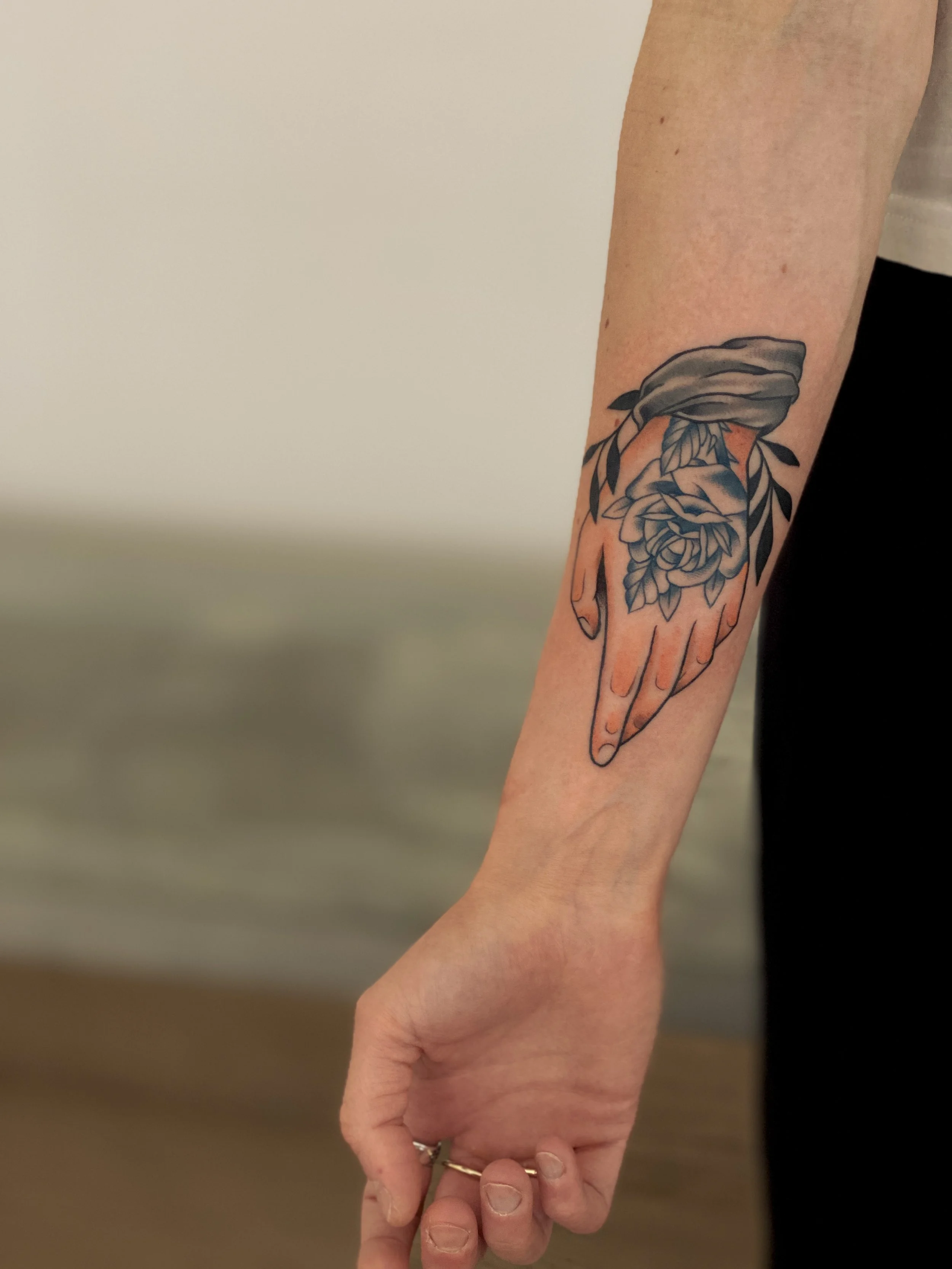 Tatovering af en hånd med roser på underarmen.