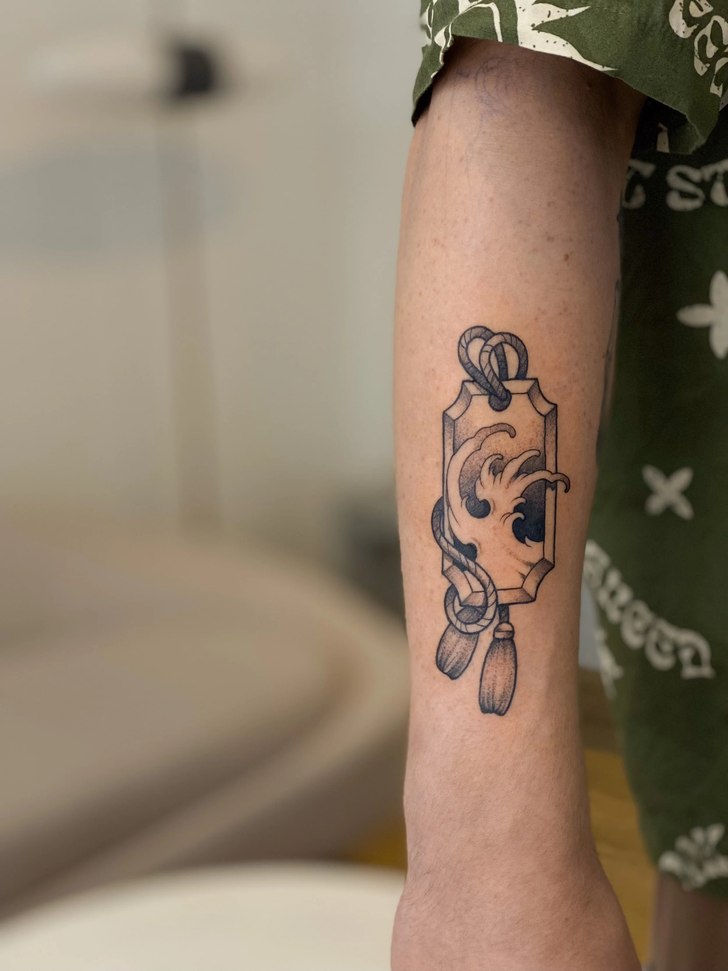 Tatovering af et kaffekrus med dampene stiger op, på personens underarm.