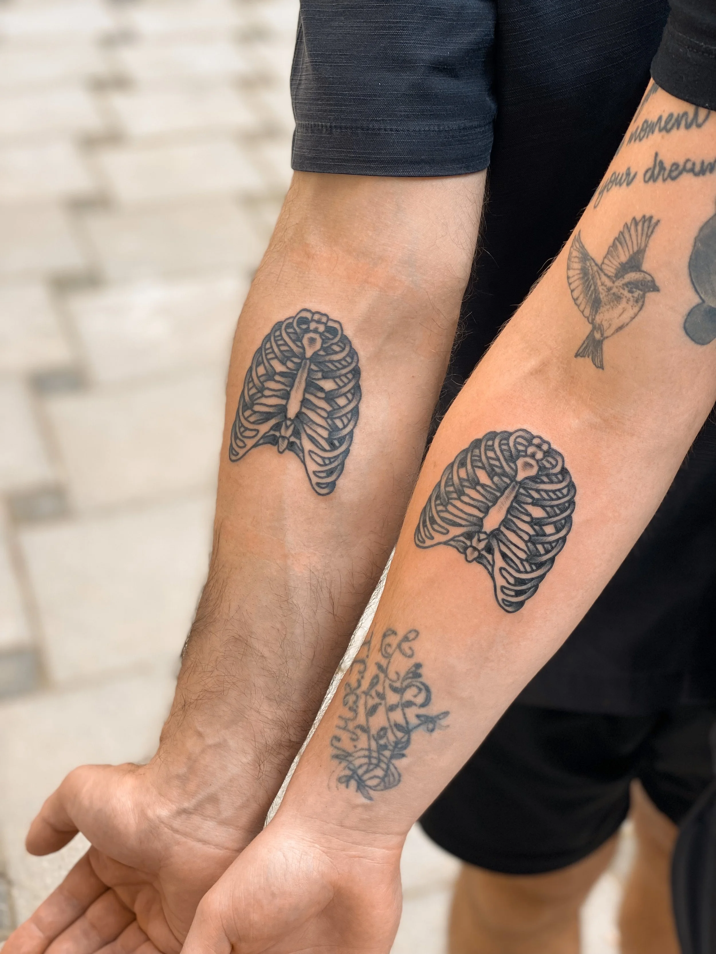 To personer med matchende tatoveringer af ribbein på deres underarme.