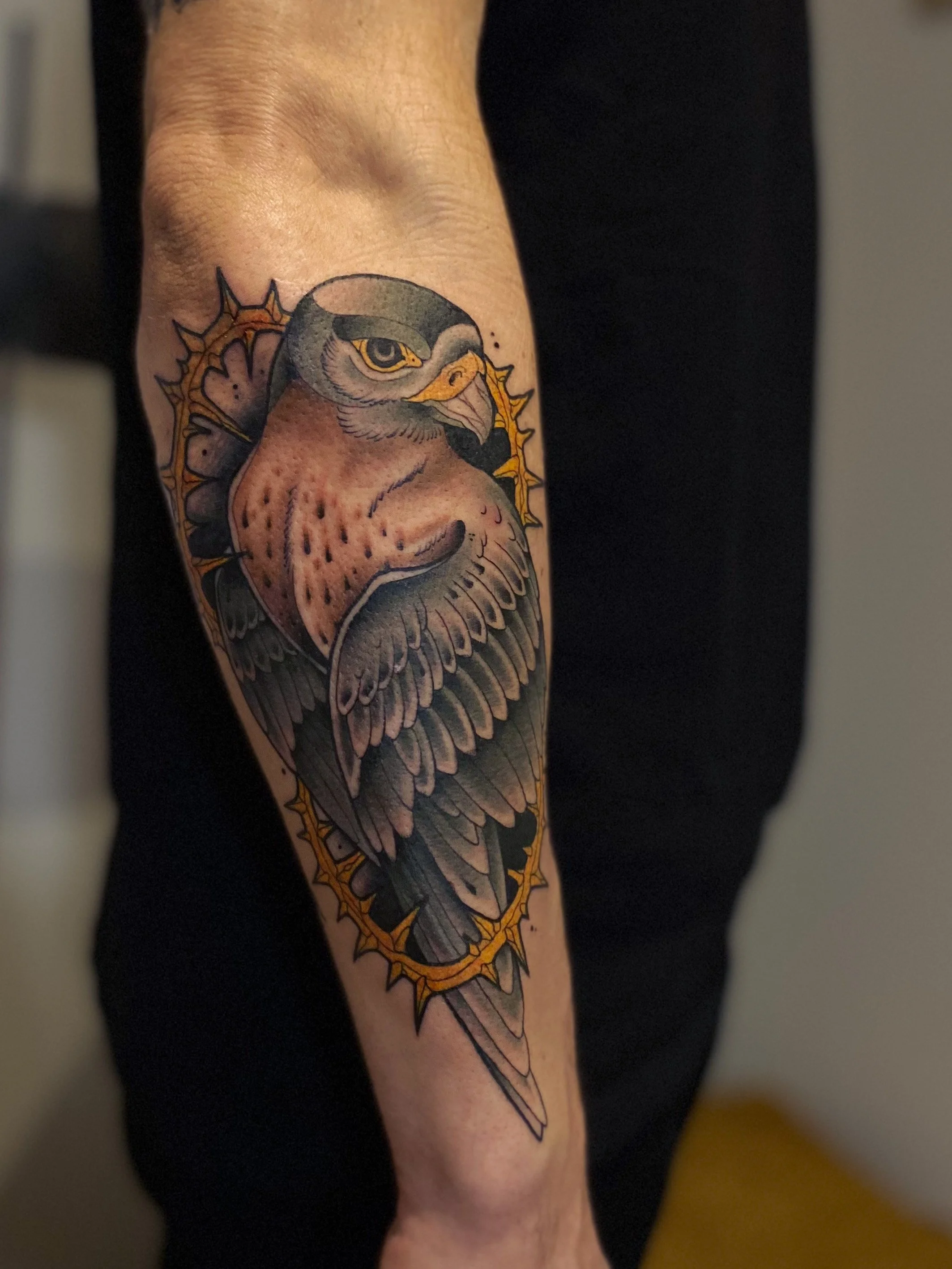 Tatovering af en ugle med en gylden torn omkring.