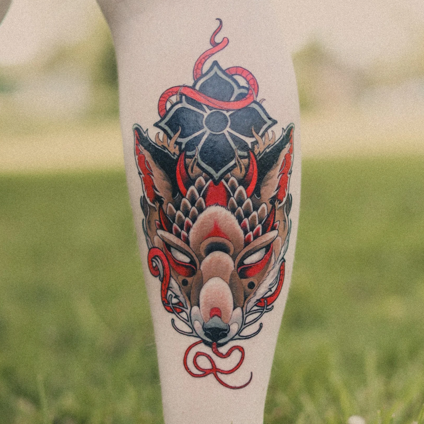 Tattoo af en fantasifuld ugleryg med snakes og blomster detaljer på en persons arm.