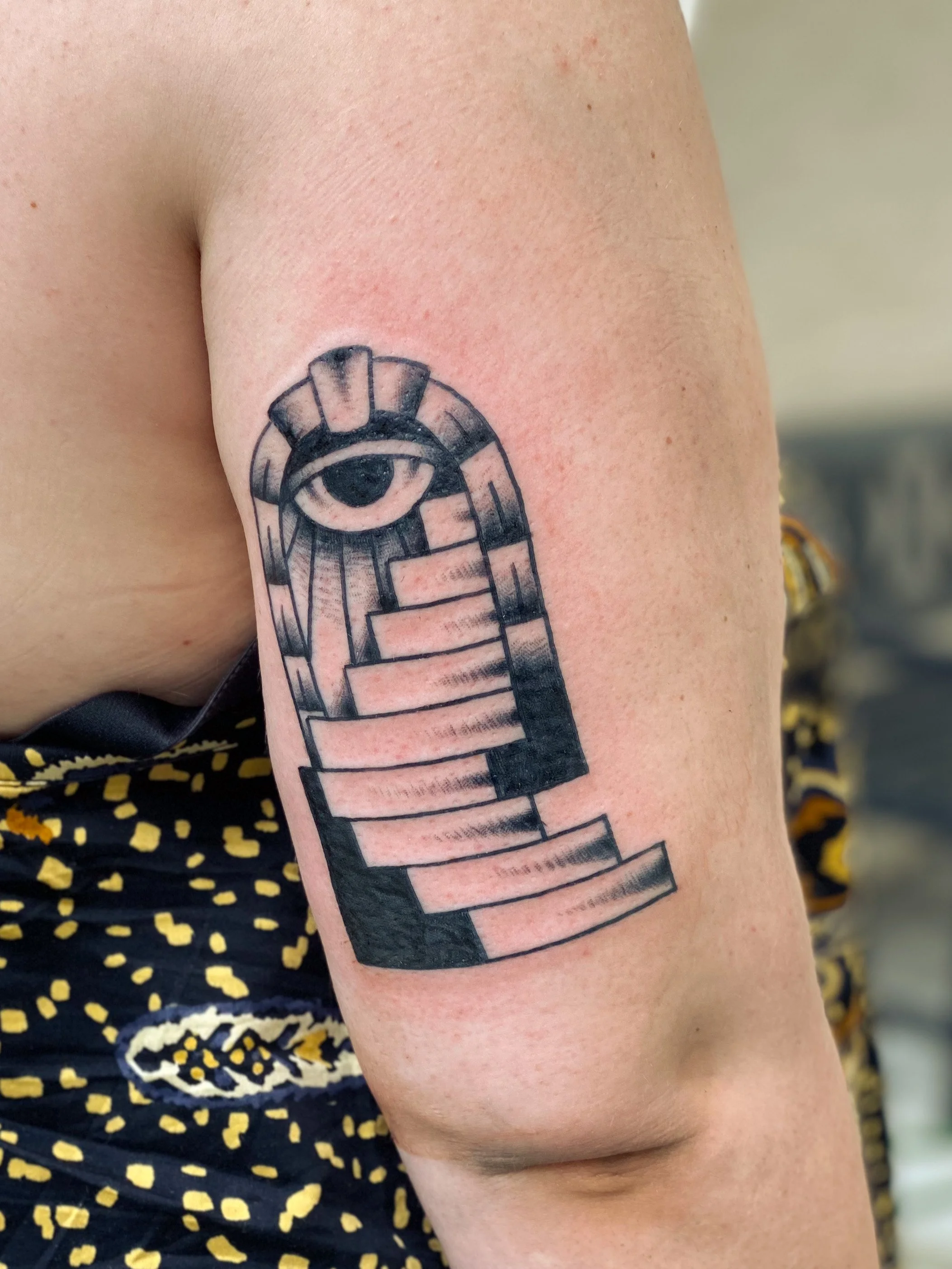 Tatovering af et øje over en trappe på overarmen