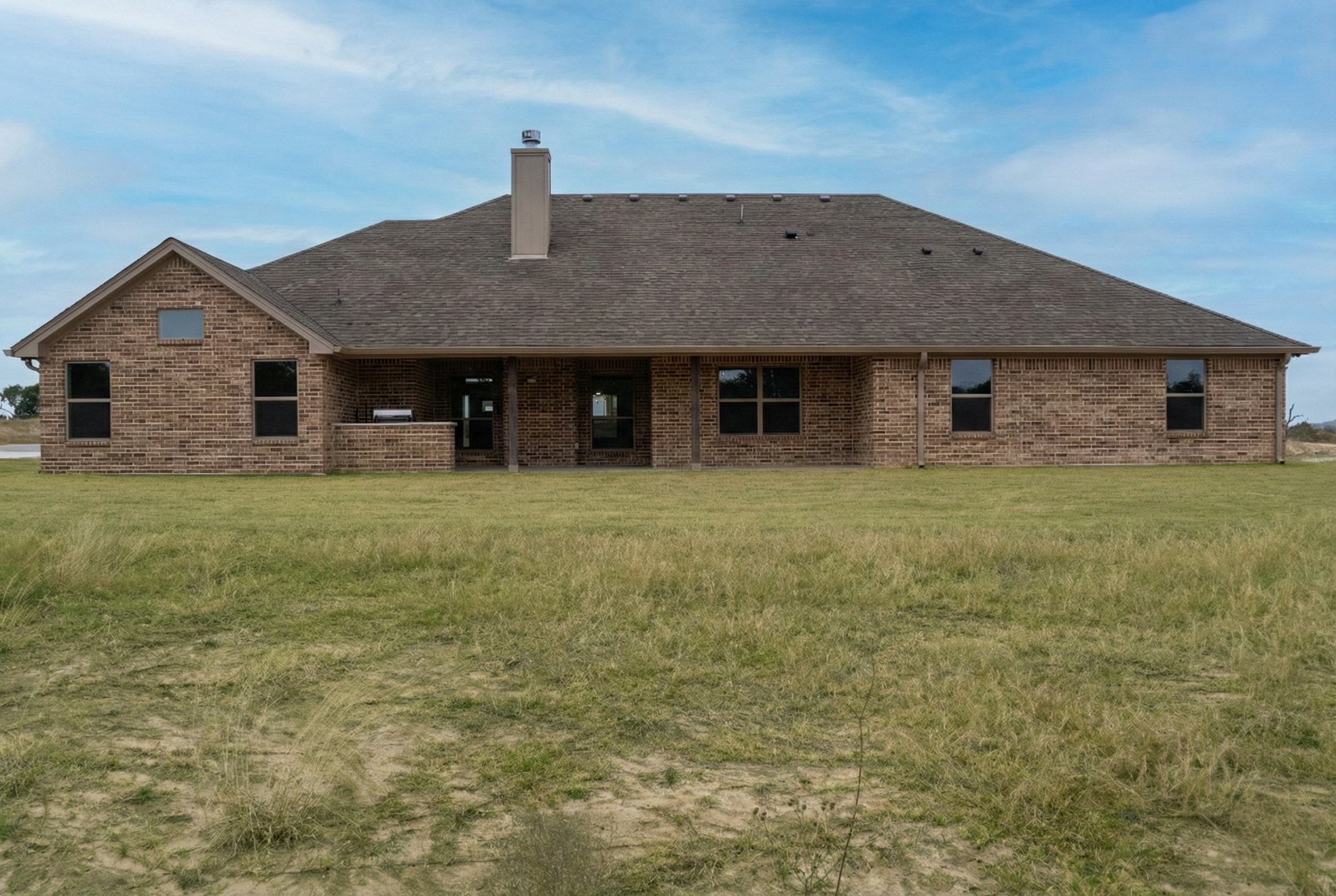 Professional real estate photography of a vacant 3,500 sq ft home exterior. Rear view featuring a covered patio and beautiful blue skies. Serving Central Texas listings in Austin, Round Rock, Georgetown, Killeen, Temple, and Waco – Focus Point Media.