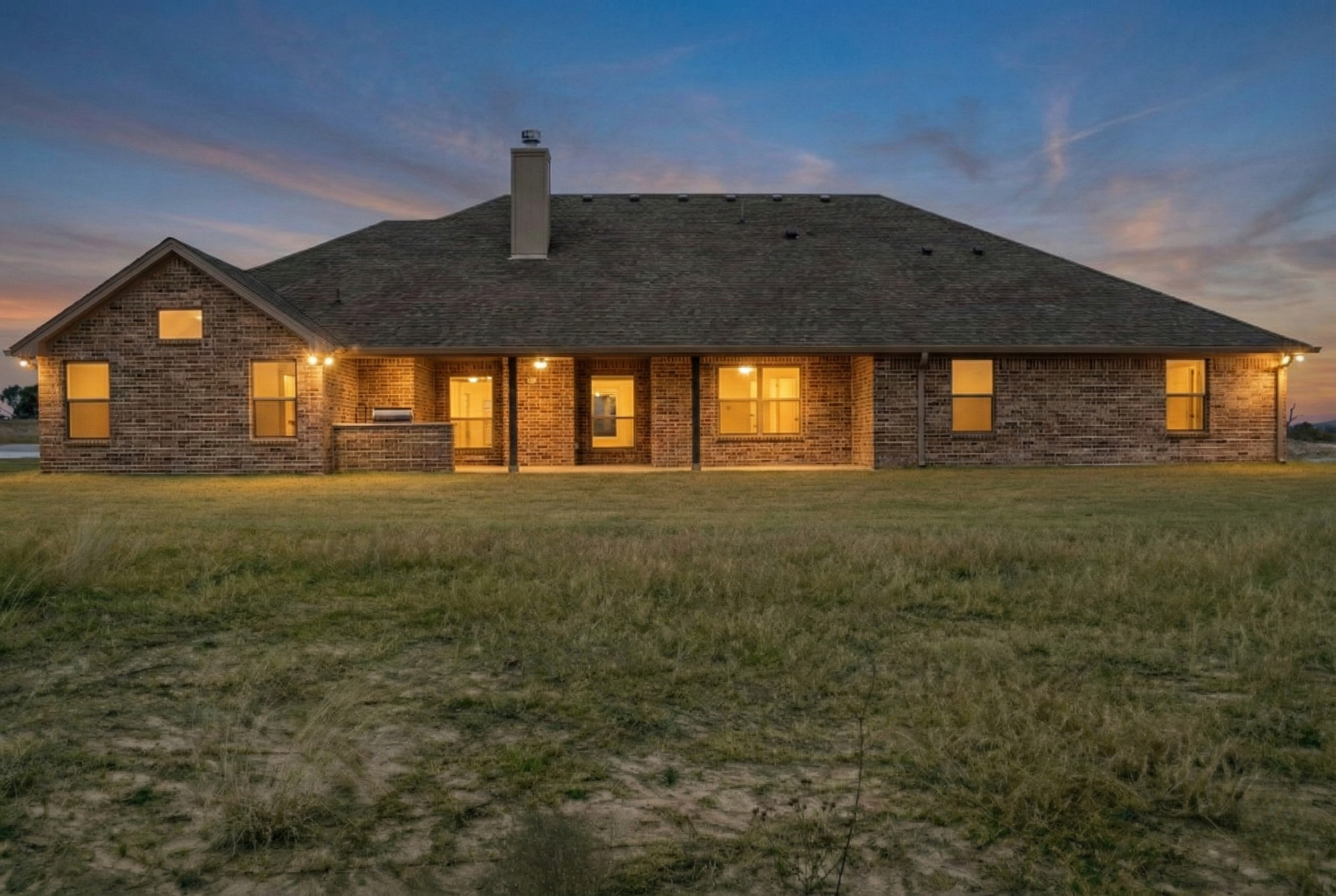 Premium twilight real estate photography of a vacant 3,500 sq ft home. The exterior is glowing with all lights on against a beautiful purplish blue sky. High-end dusk photography for Central Texas listings in Austin, Round Rock, Georgetown, Killeen, 
