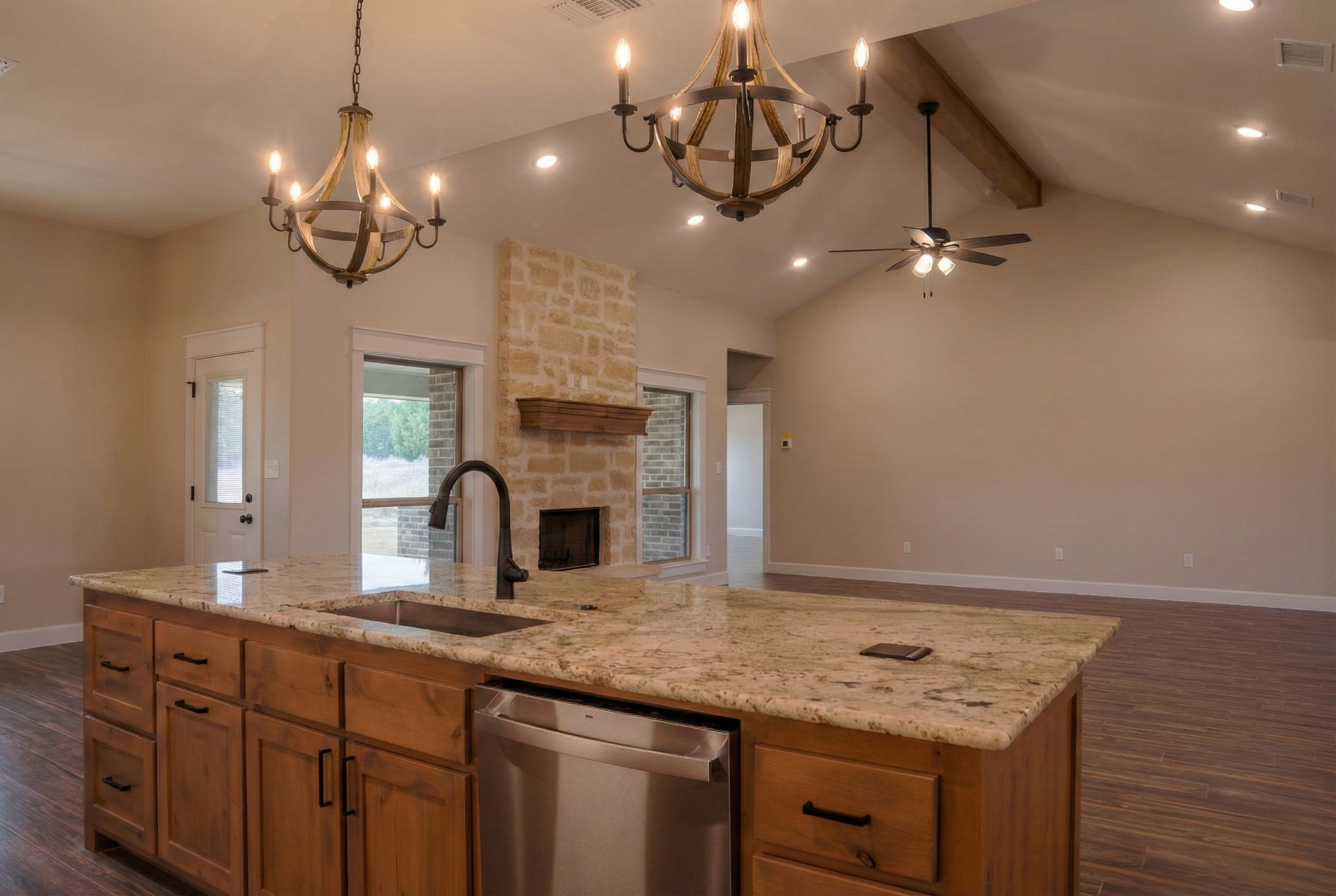 Professional real estate photography of a vacant 3,500 sq ft luxury home. Interior view from the kitchen island featuring upscale pendant lighting, a far-end fireplace, and abundant natural light from large windows. Serving Austin, Round Rock, George