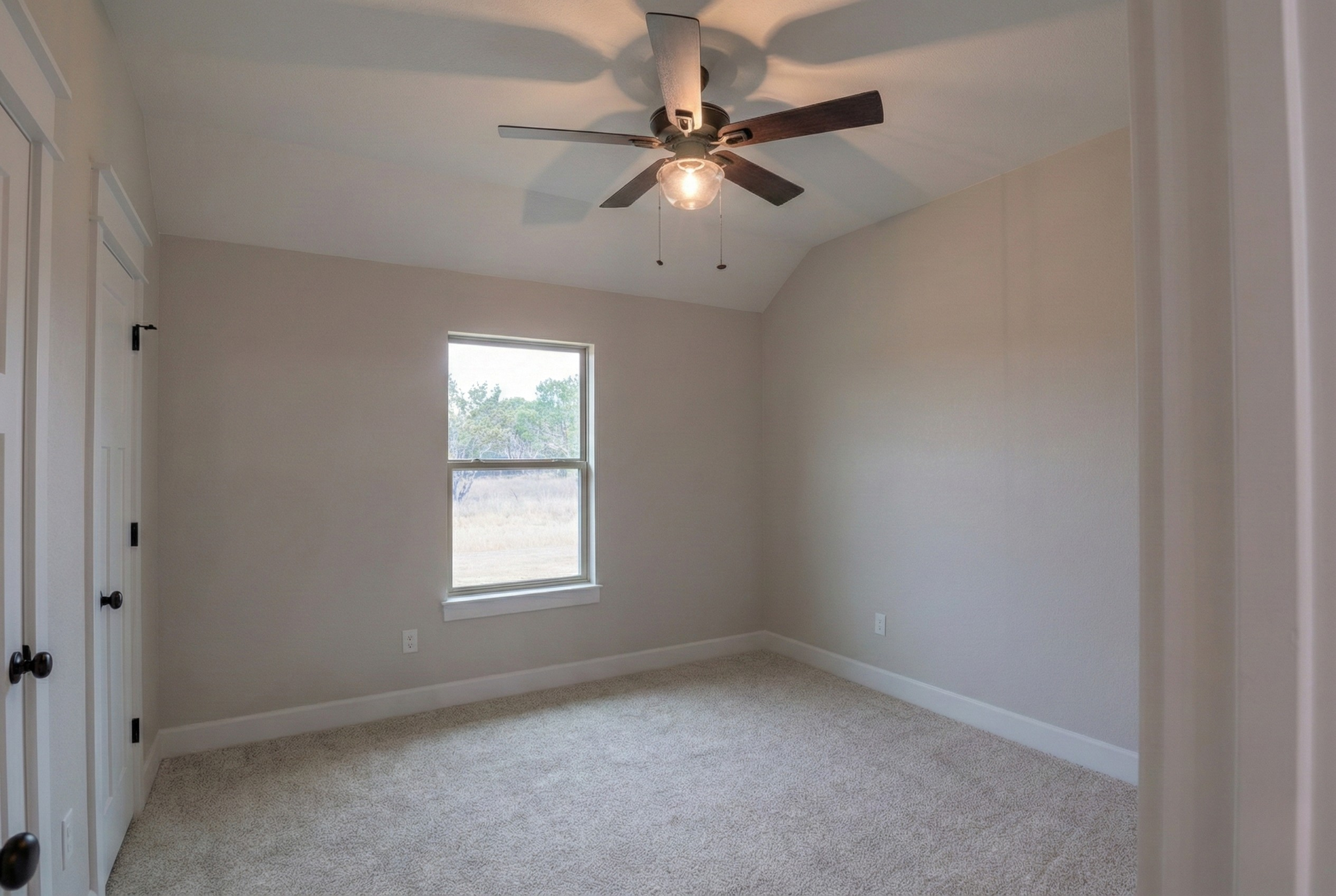 Professional real estate photography of a spacious vacant spare bedroom in a 3,500 sq ft luxury home. Interior view from the doorway featuring ample floor space and natural light from a large window. Serving Austin, Round Rock, Georgetown, Killeen, T