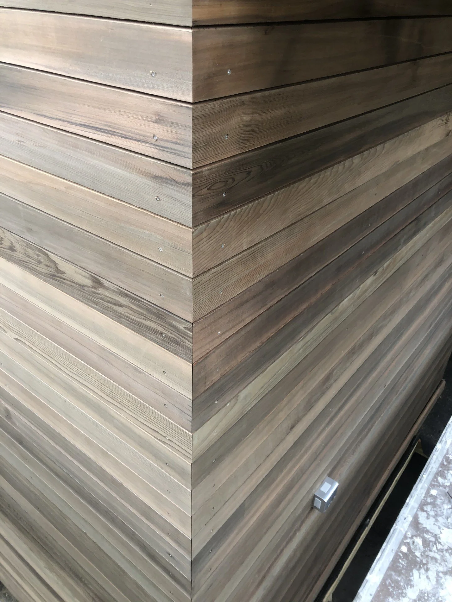 Kjempehaug med treplanker av ulike tresorter, stablet i lag, med en liten elektrisk kobling og en elektrisk kontakt i bunnen av stabelen.