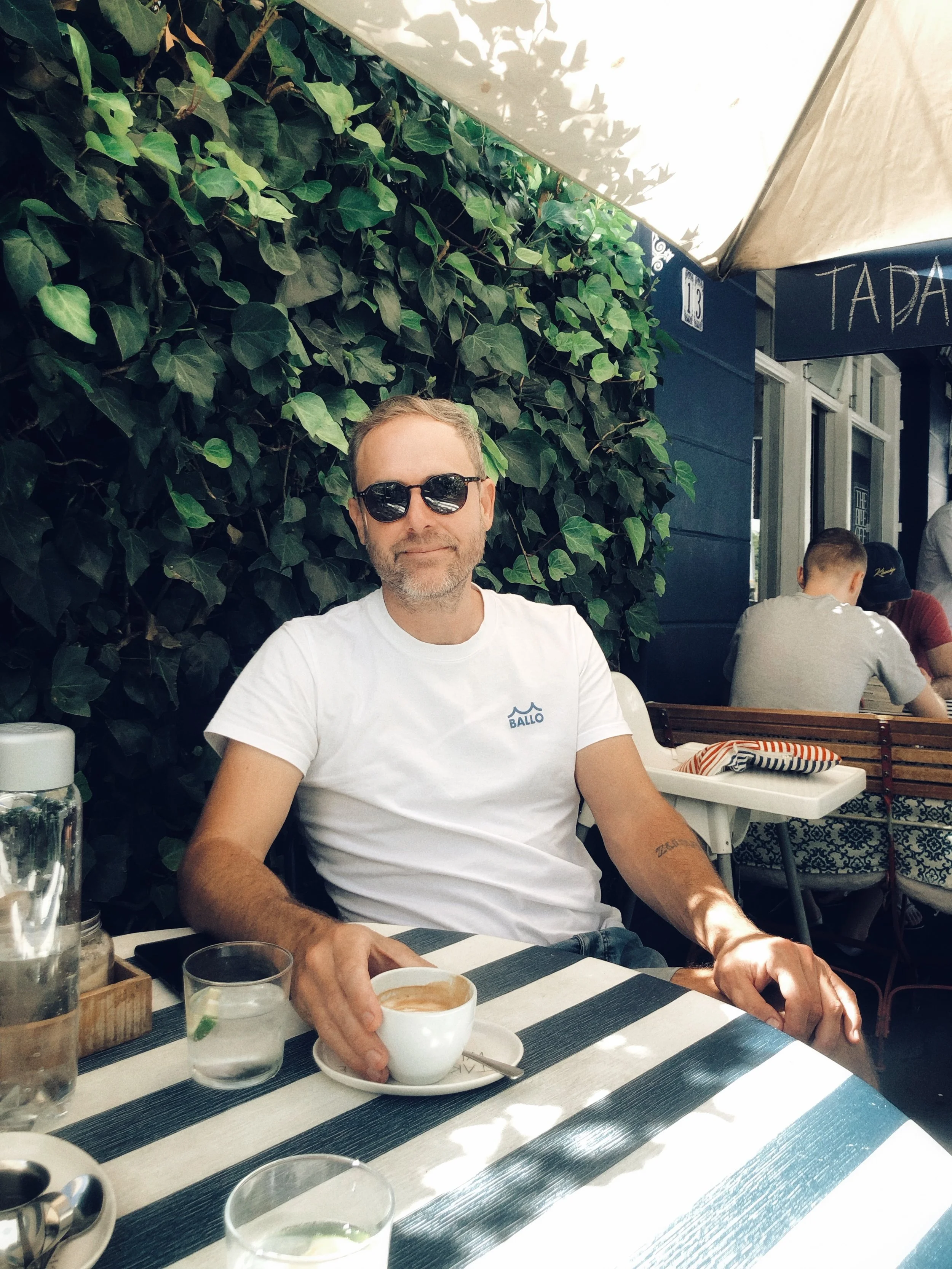 Alex with coffee: Brand strategist Alex Hayn at a consultation, acting as a sounding board for owners navigating generational change or brand expansion.