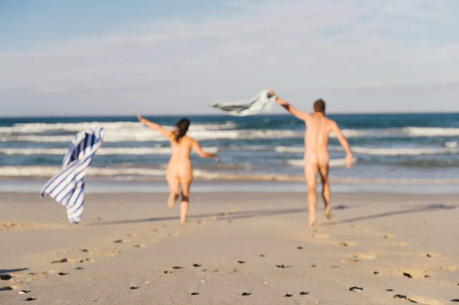 Couple on beach with towel: Capturing the authentic truth of a guest’s experience to verify if marketing claims of intimacy and freedom are being delivered.