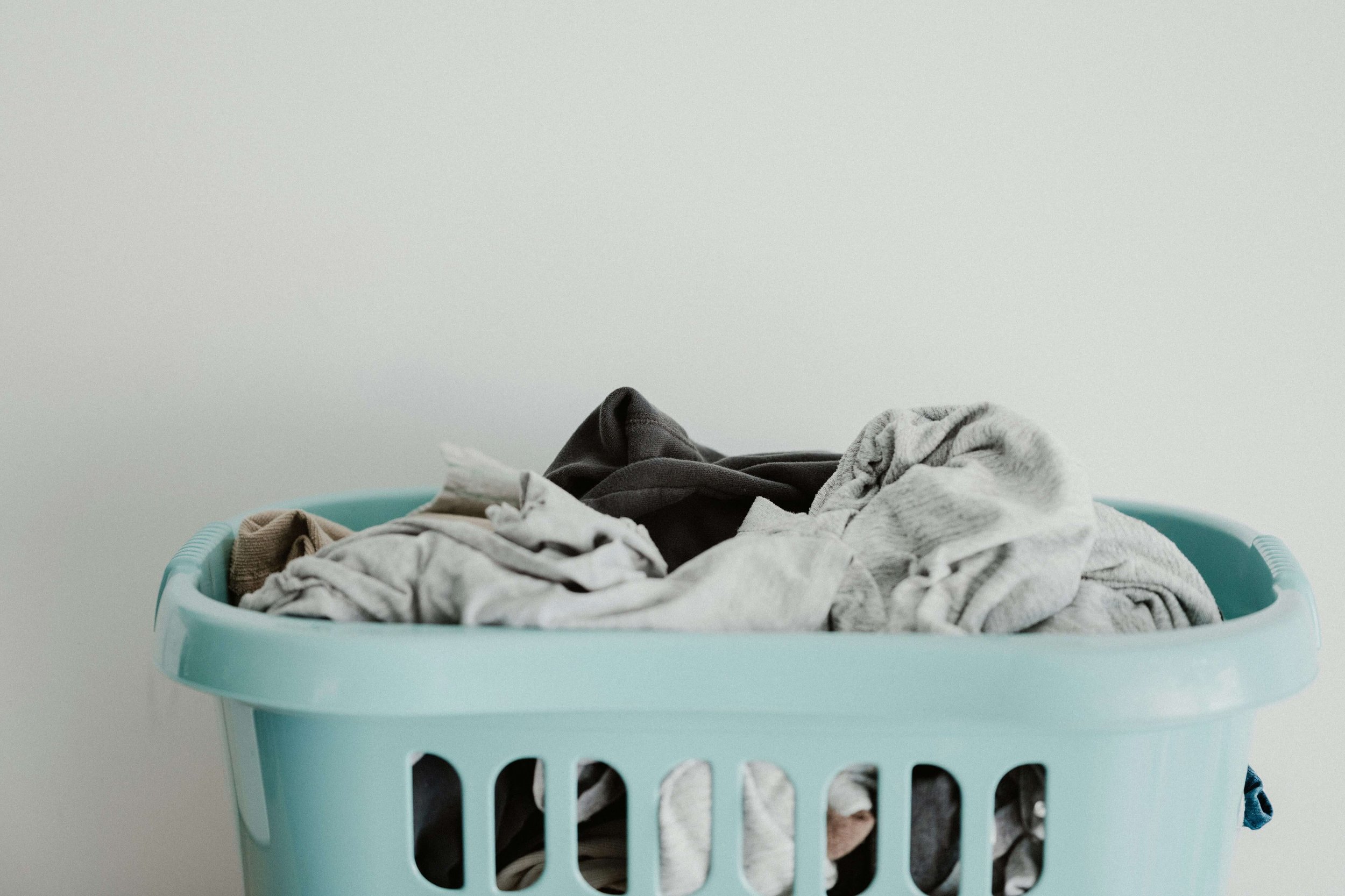 Light blue laundry basket full of clothes.